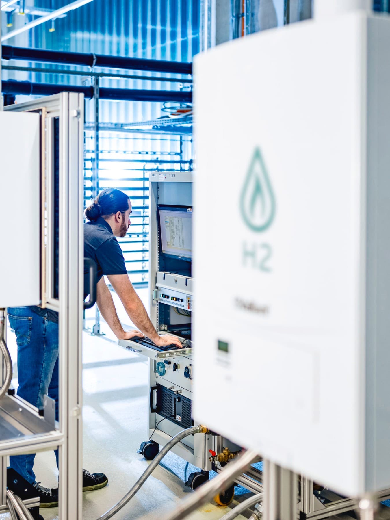 Installateur sur un banc d'essai vérifiant les données d'un essai avec de l'hydrogène | Vaillant