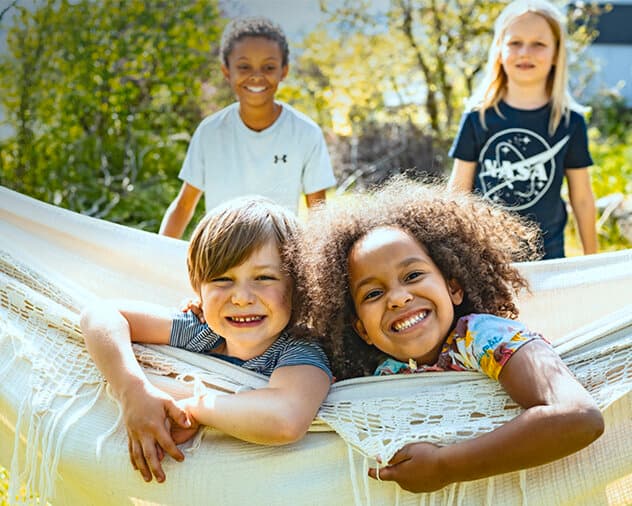Des enfants jouent dans un hamac dans un jardin | Vaillant