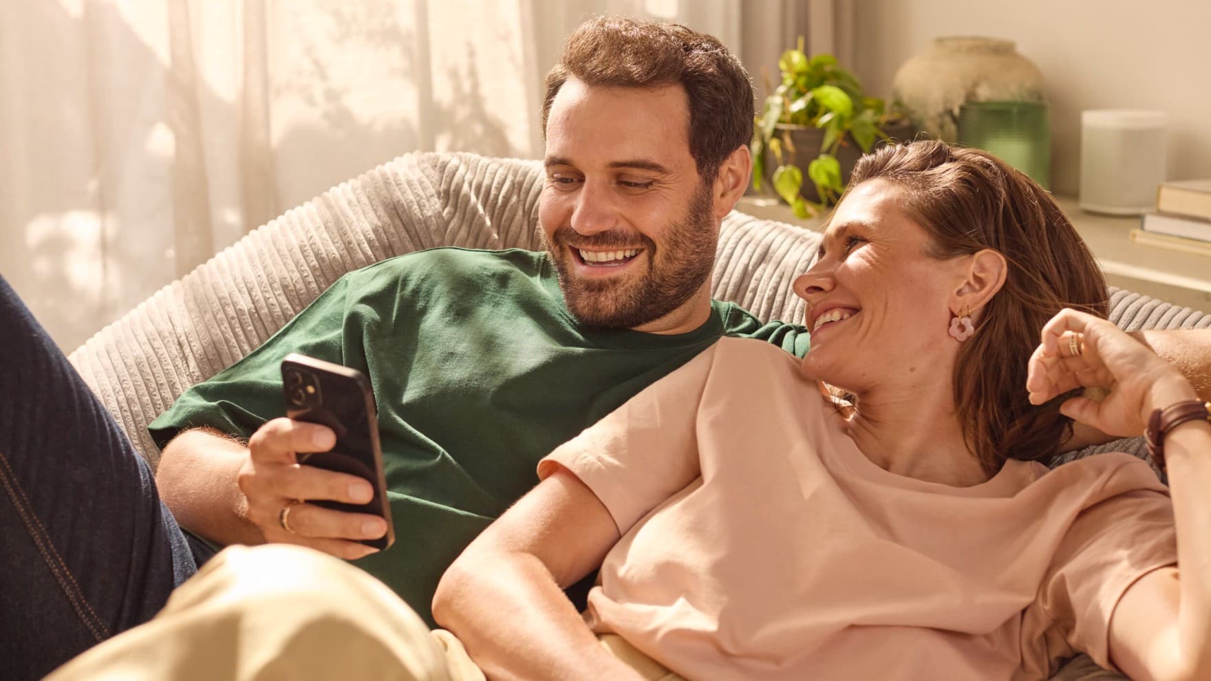 Couple assis sur un canapé regardant un téléphone | Vaillant