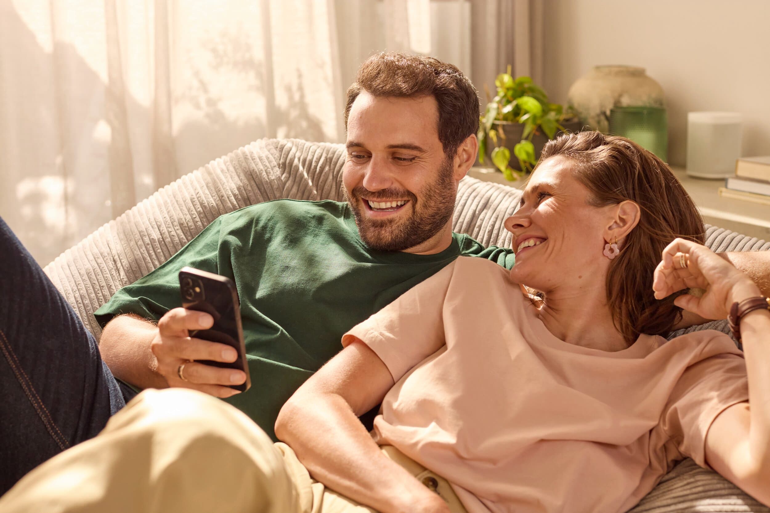 Couple pilotant leur système de chauffage depuis un téléphone | Vaillant