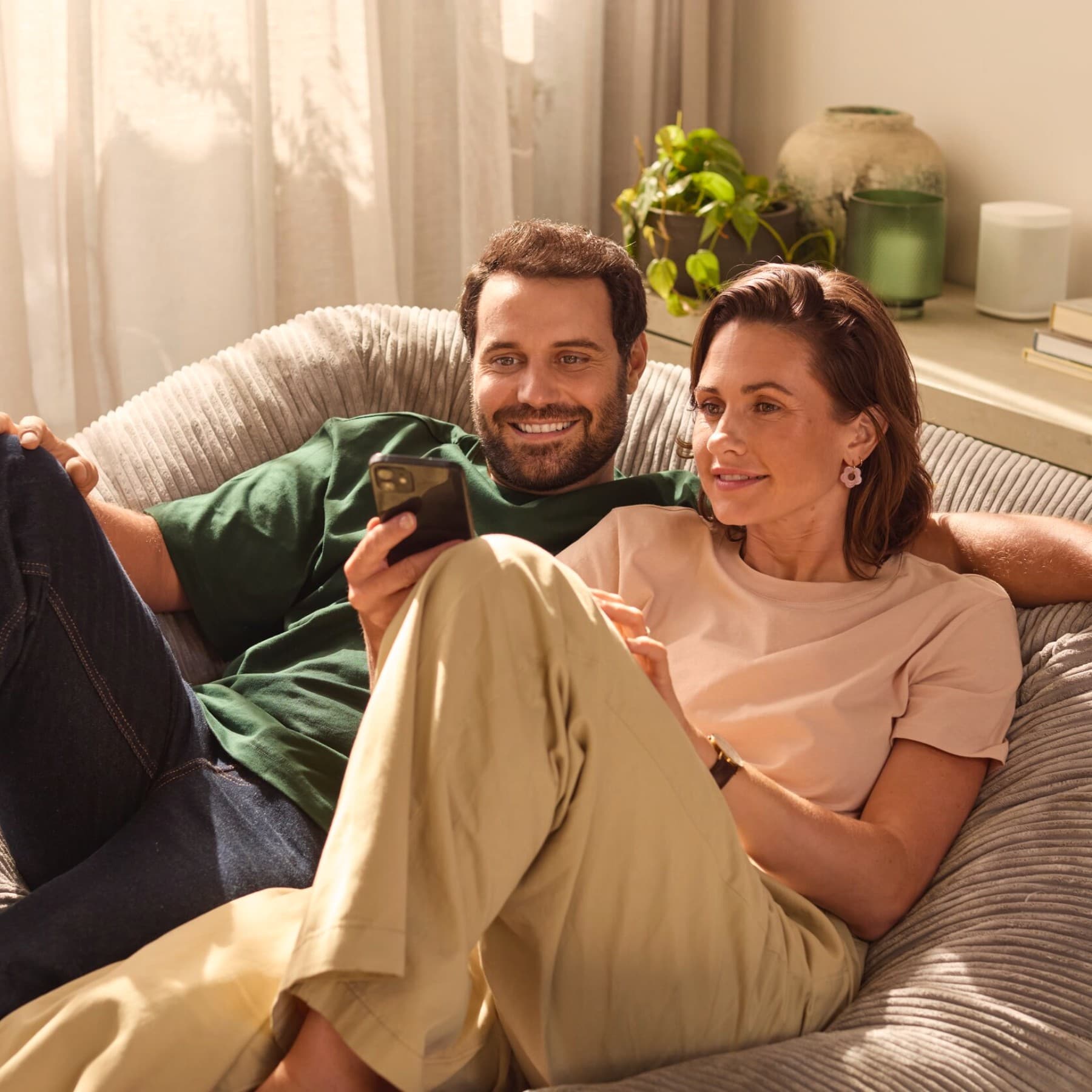 Un couple assis côte à côte, les yeux rivés sur leur téléphone | Vaillant