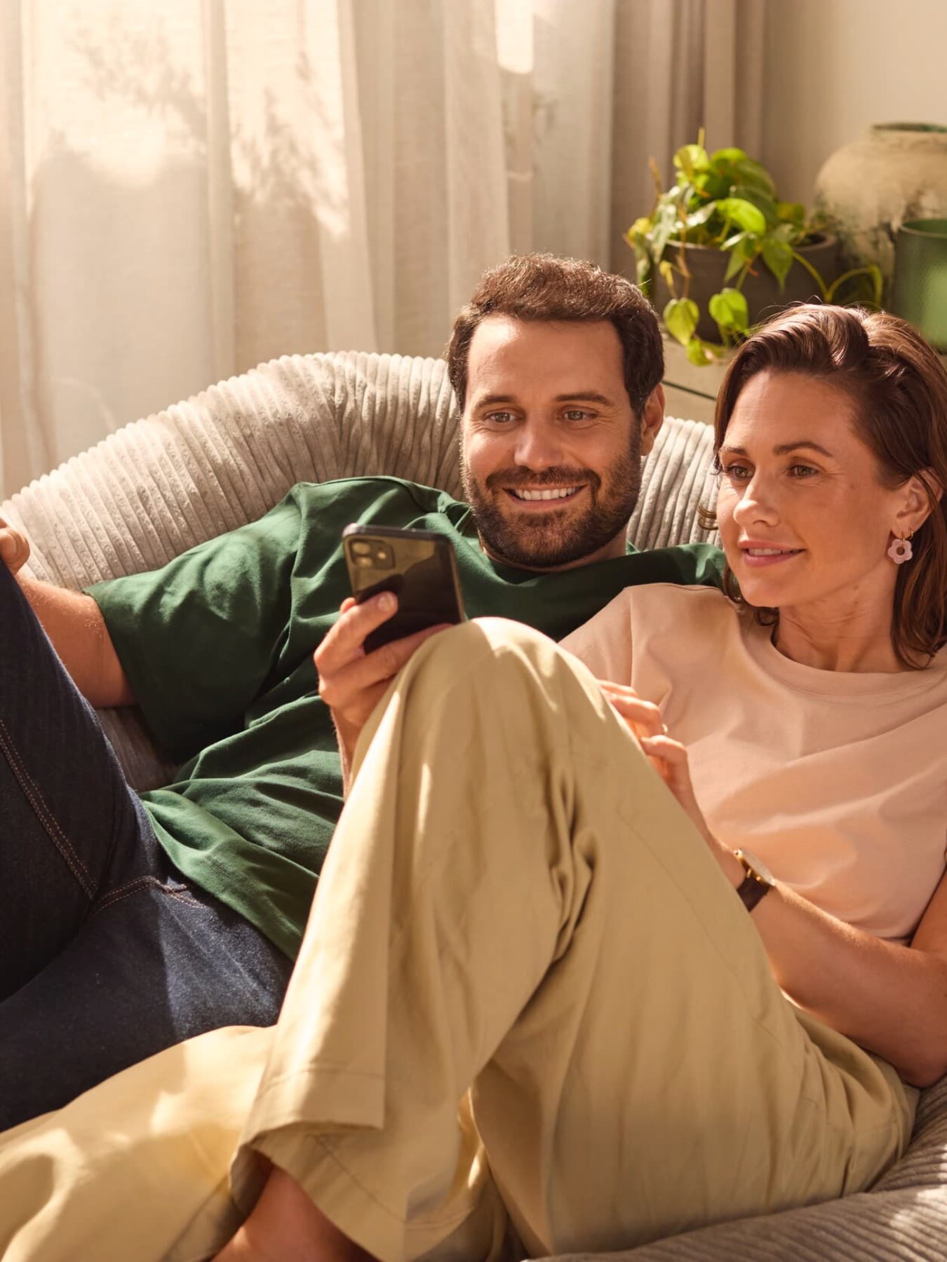 Couple assis sur un canapé regardant un smartphone | Vaillant