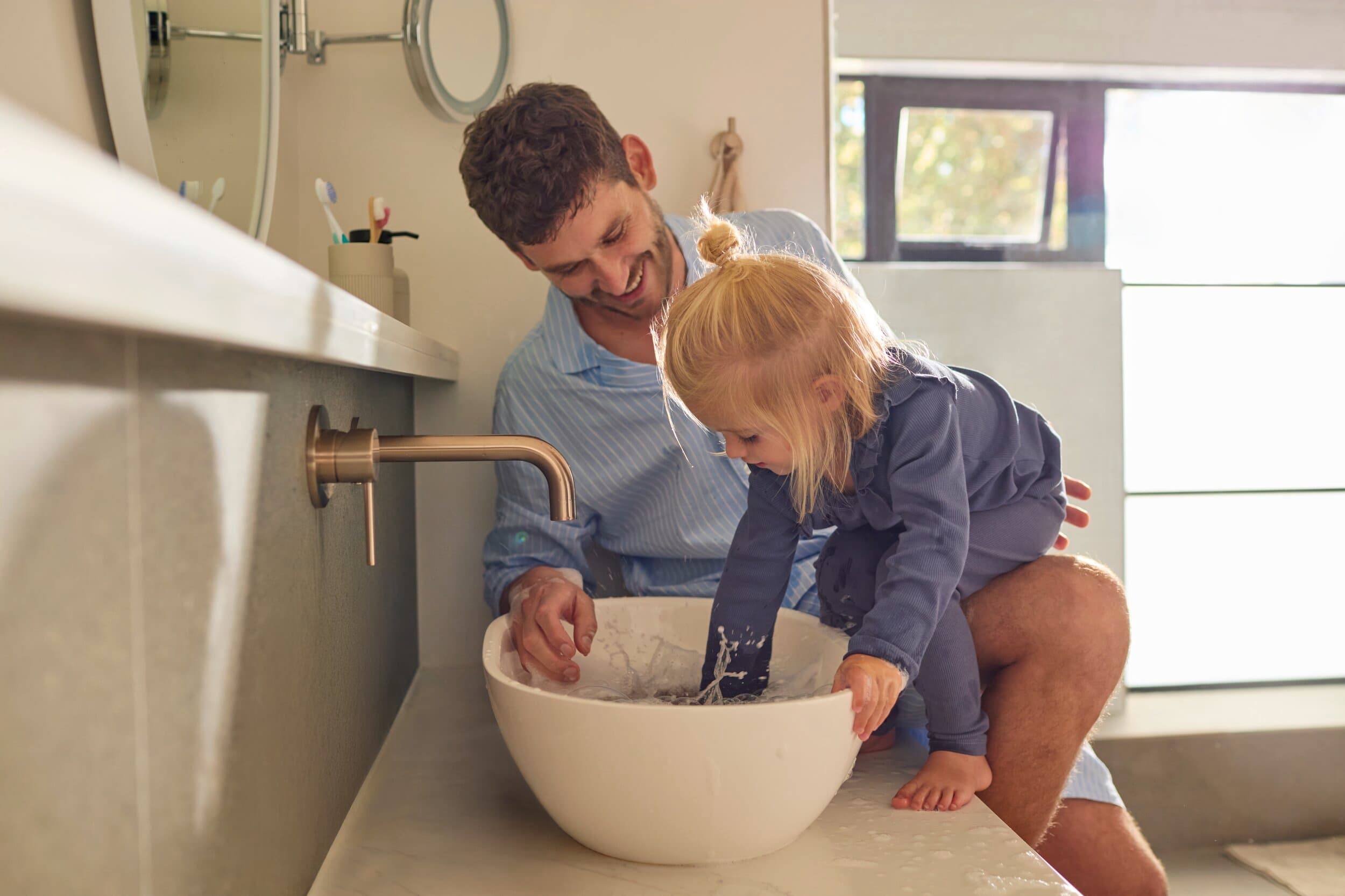 Un père et sa fille jouant avec de l'eau dans une vasque | Vaillant