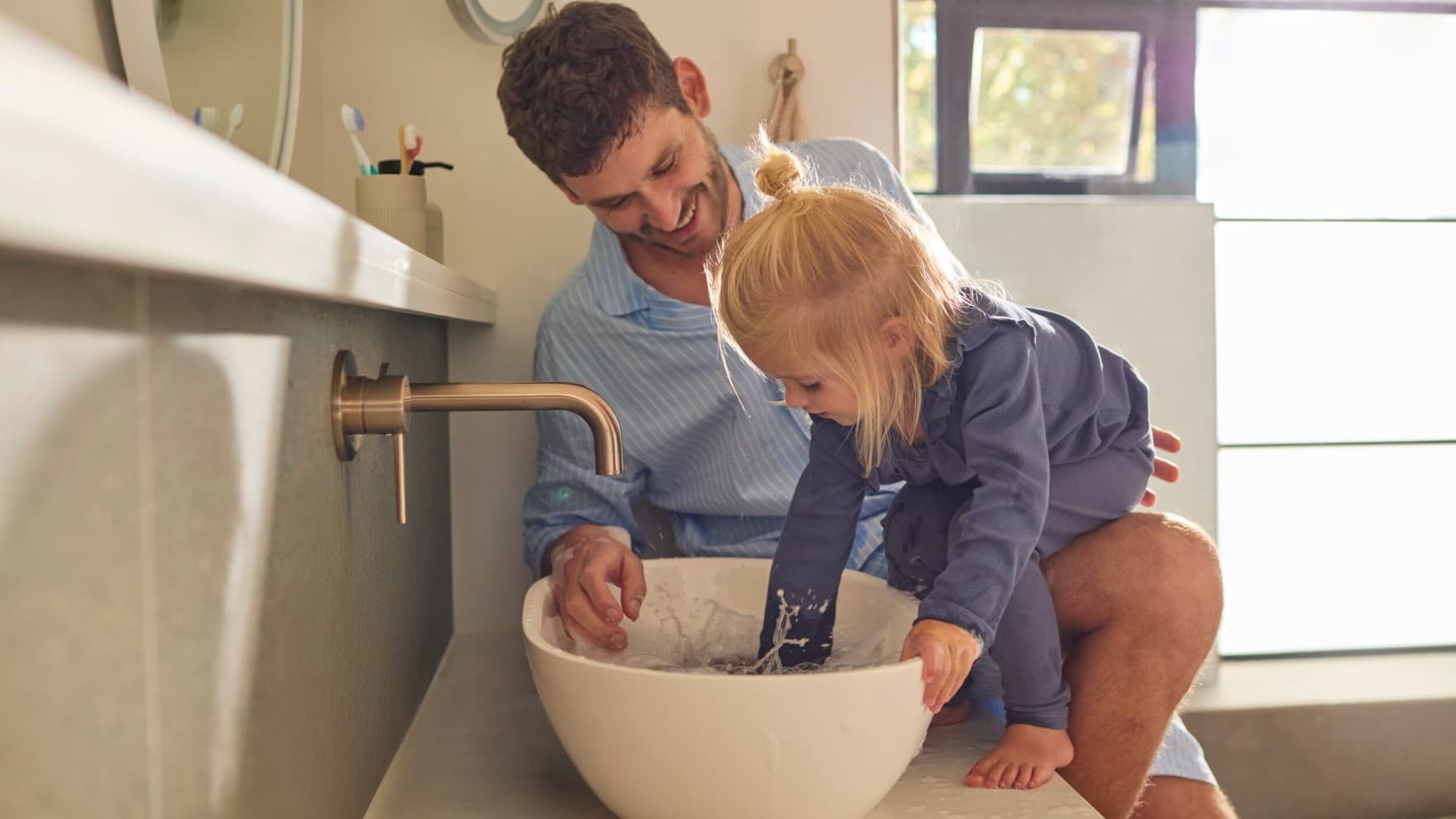 Un père et sa fille jouant avec de l'eau dans un évier | Vaillant