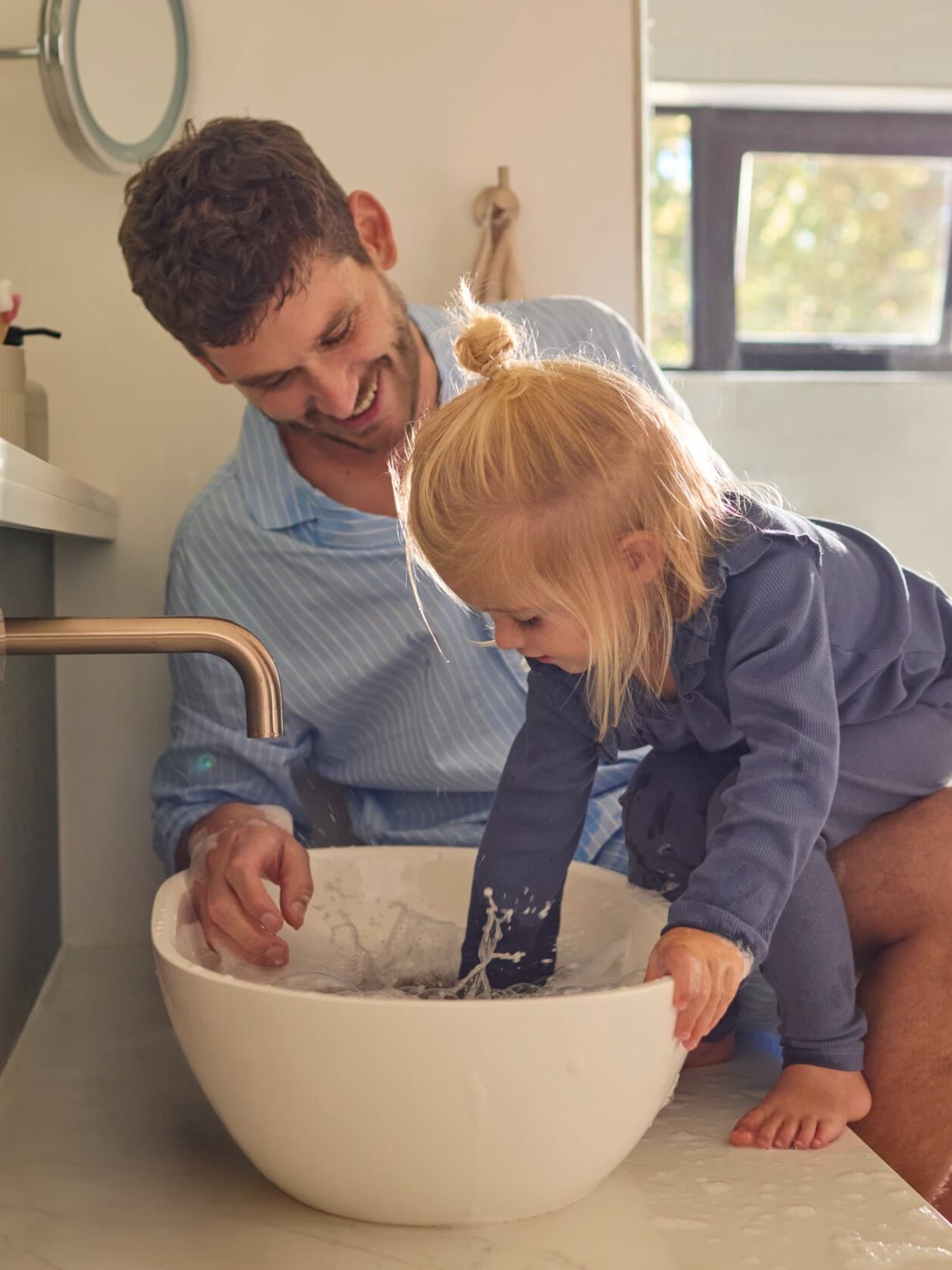 Un père et sa fille jouant avec de l'eau dans un évier | Vaillant