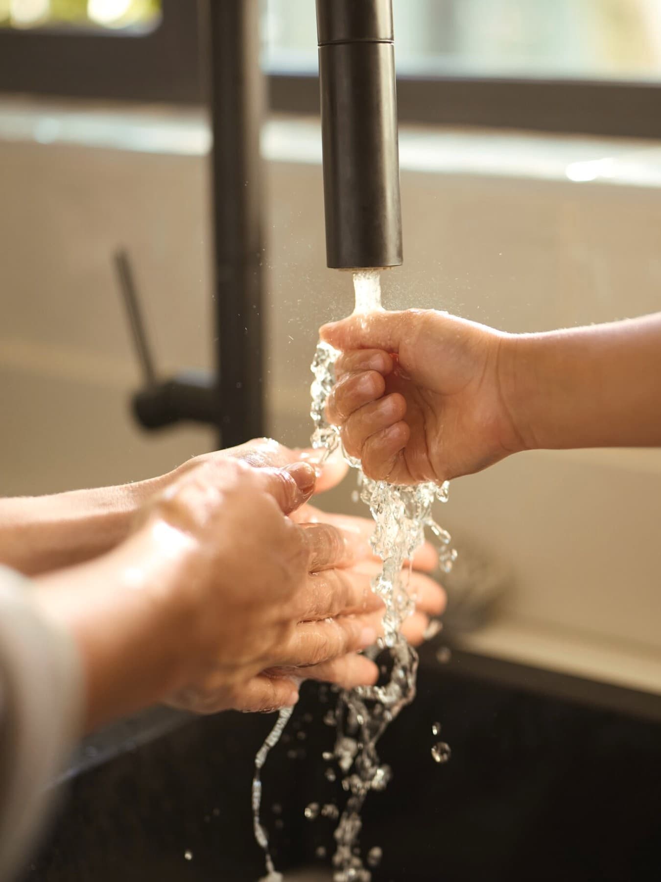 Une femme et un enfant se tenant la main sous l'eau courante | Vaillant
