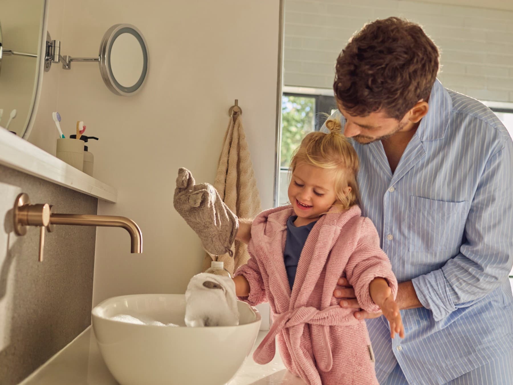 Le père et la fille sont debout ensemble devant l'évier et jouent avec l'eau | Vaillant