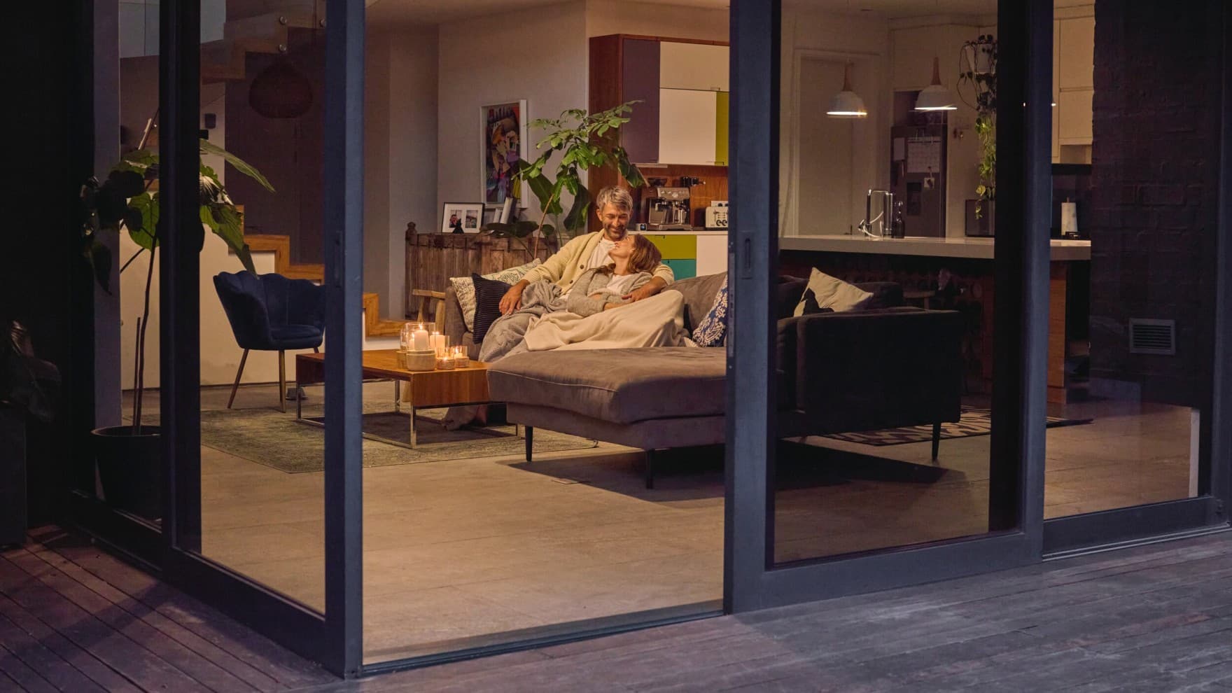 Couple assis sur le canapé avec la porte-fenêtre ouverte | Vaillant
