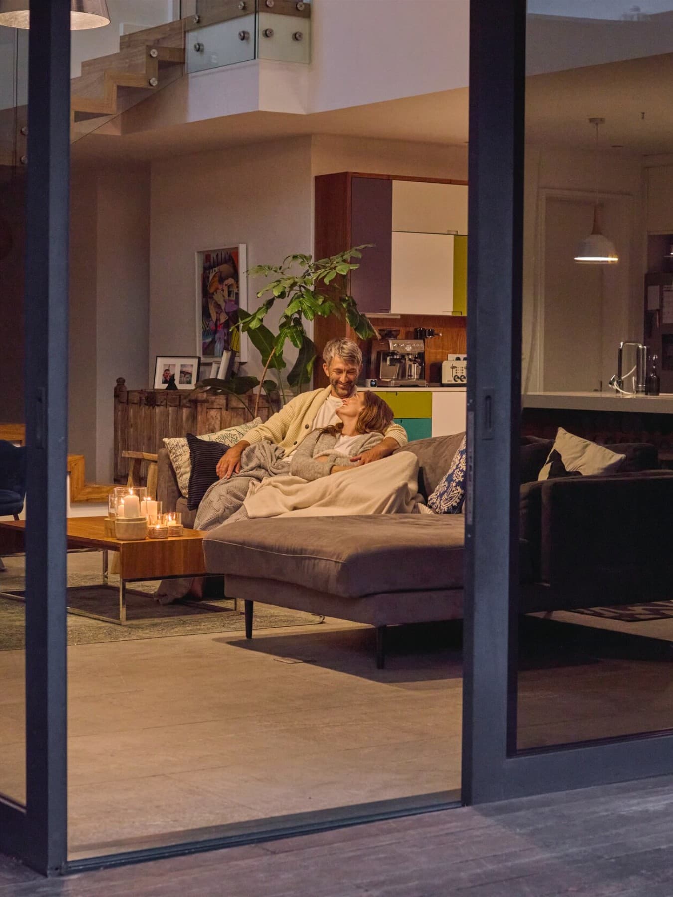 Couple assis sur le canapé avec la porte-fenêtre ouverte | Vaillant