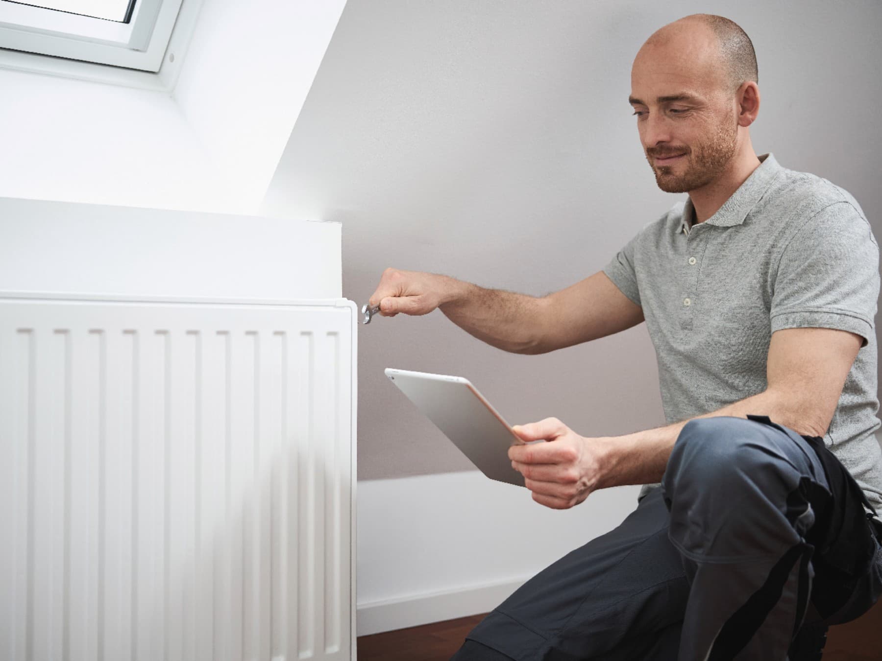 Un installateur ouvre la valve de purge d'air d'un radiateur | Vaillant