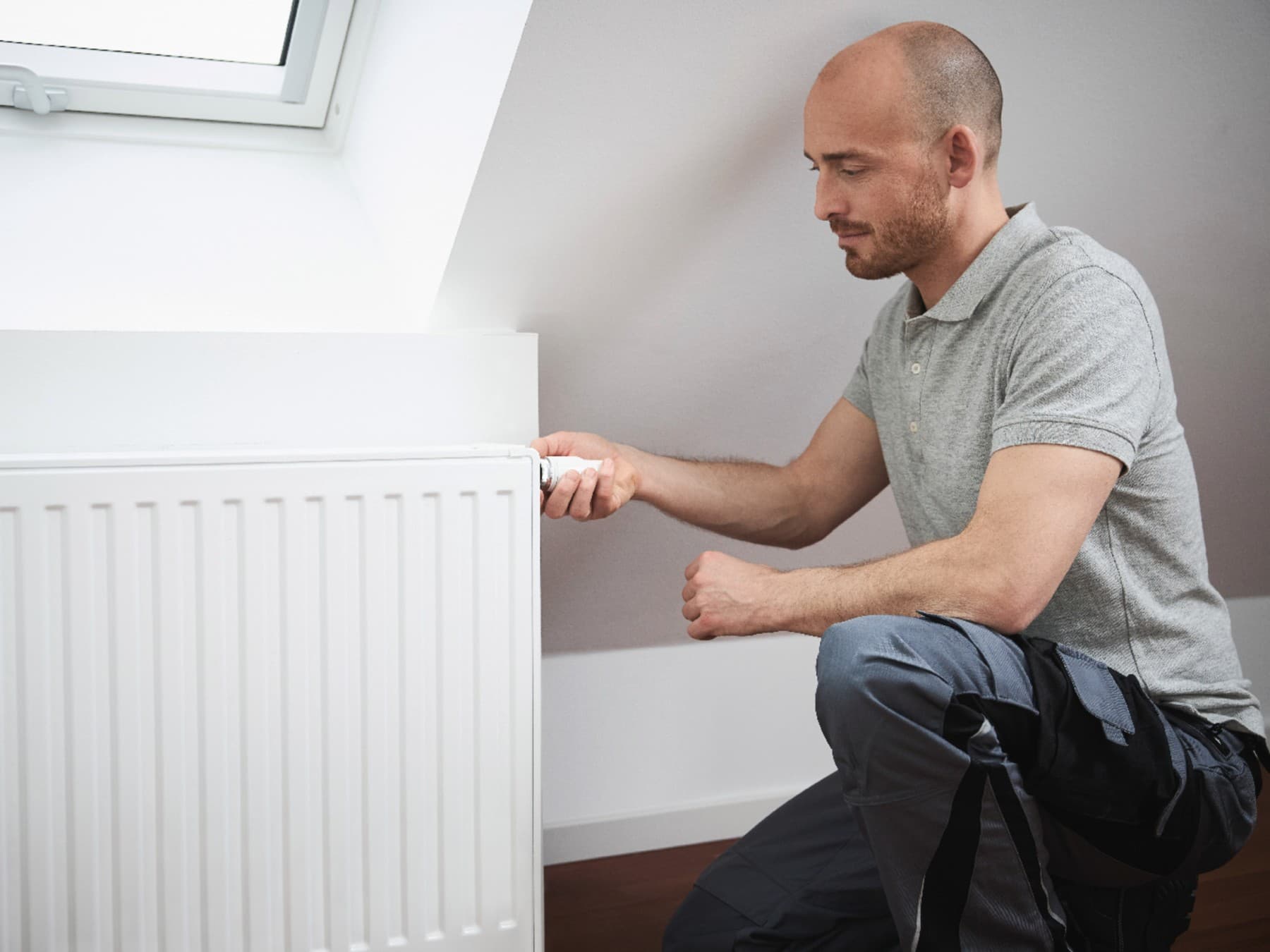 Un homme règle le radiateur avec son thermostat thermostatique