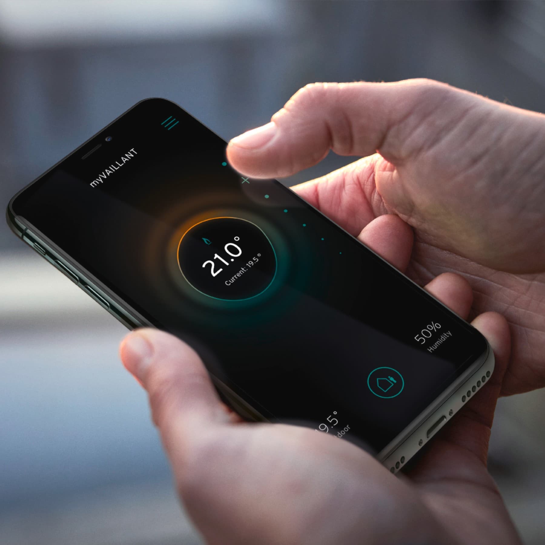 Homme tenant son smartphone dans sa main pour contrôler son thermostat à distance | Vaillant
