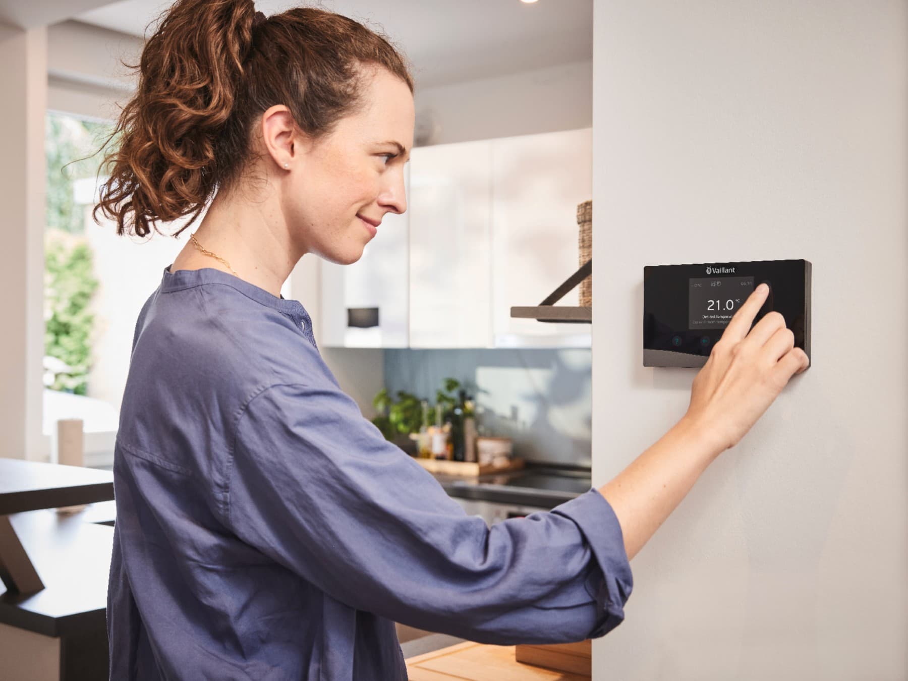 Une femme réglant son chauffage | Vaillant
