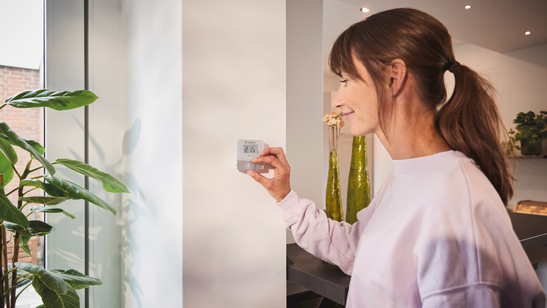 Femme utilisant le thermostat sensoROOM | Vaillant