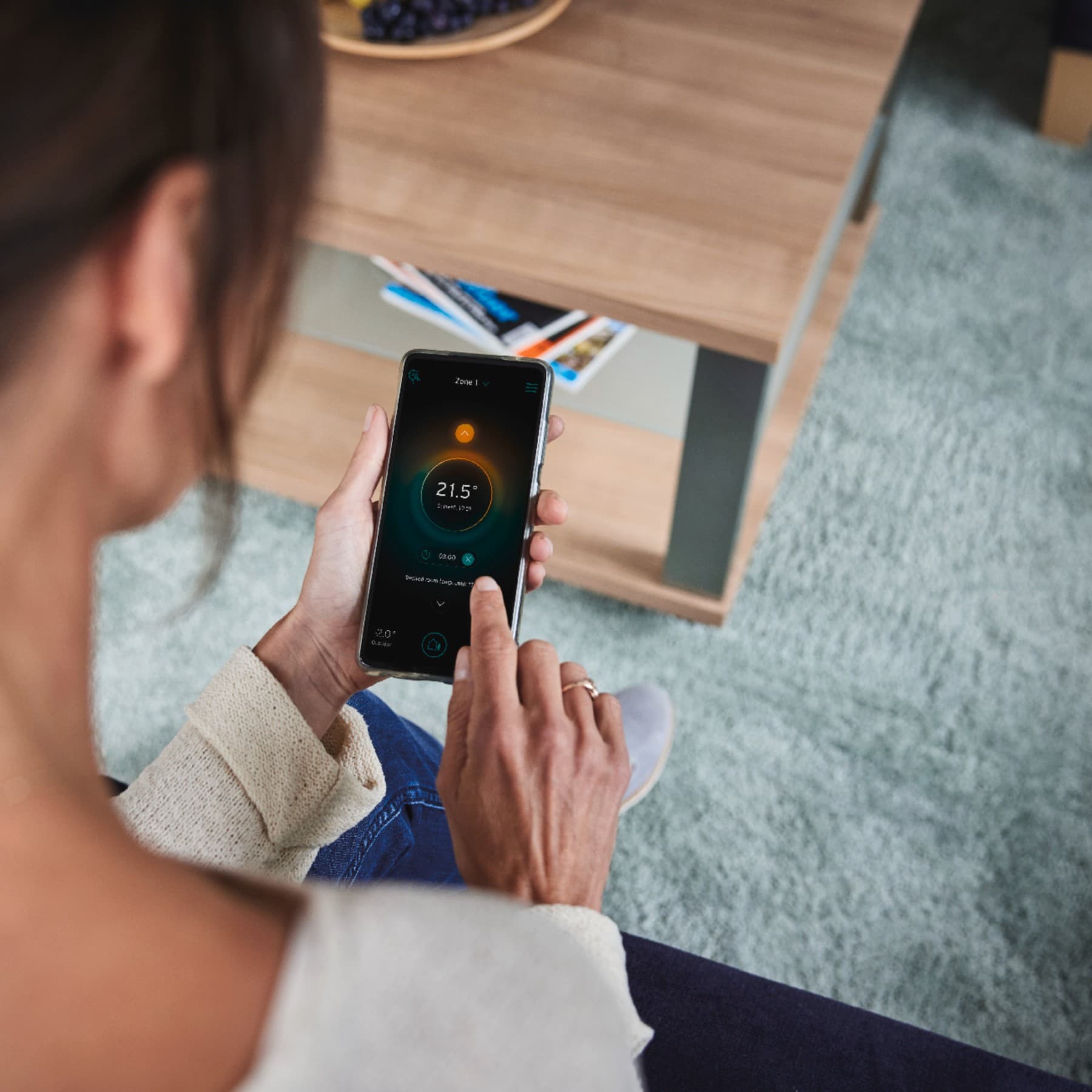 Une femme qui règle son système de chauffage via son téléphone mobile | Vaillant