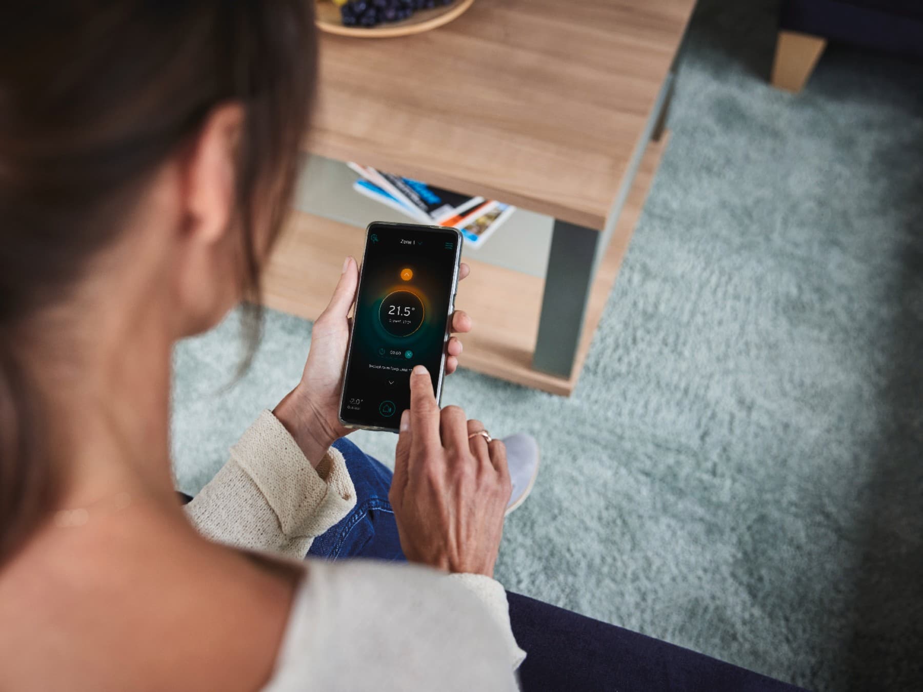 Une femme qui règle son système de chauffage via son téléphone mobile | Vaillant