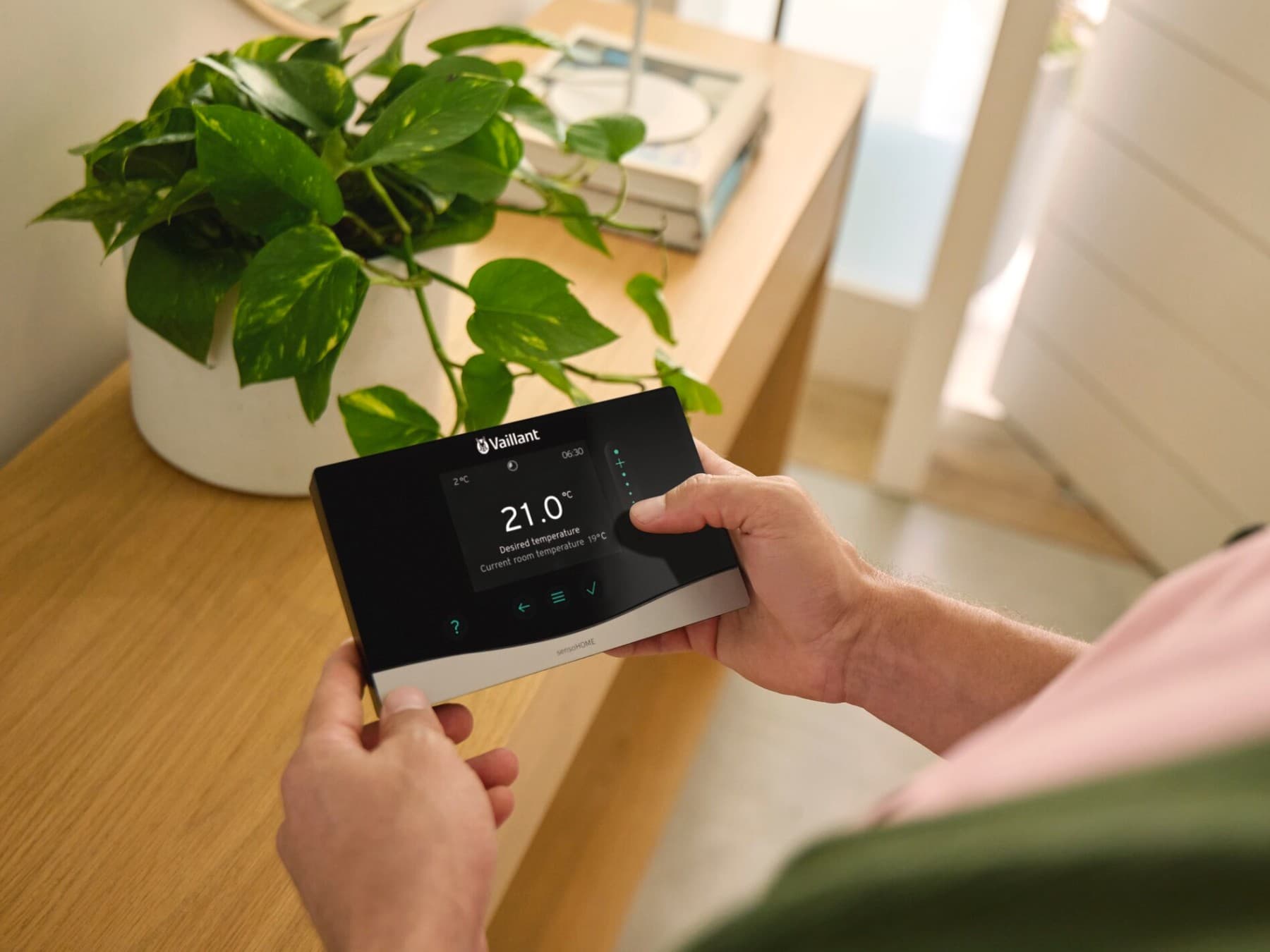 Homme tenant le régulateur sensoHOME dans ses mains | Vaillant