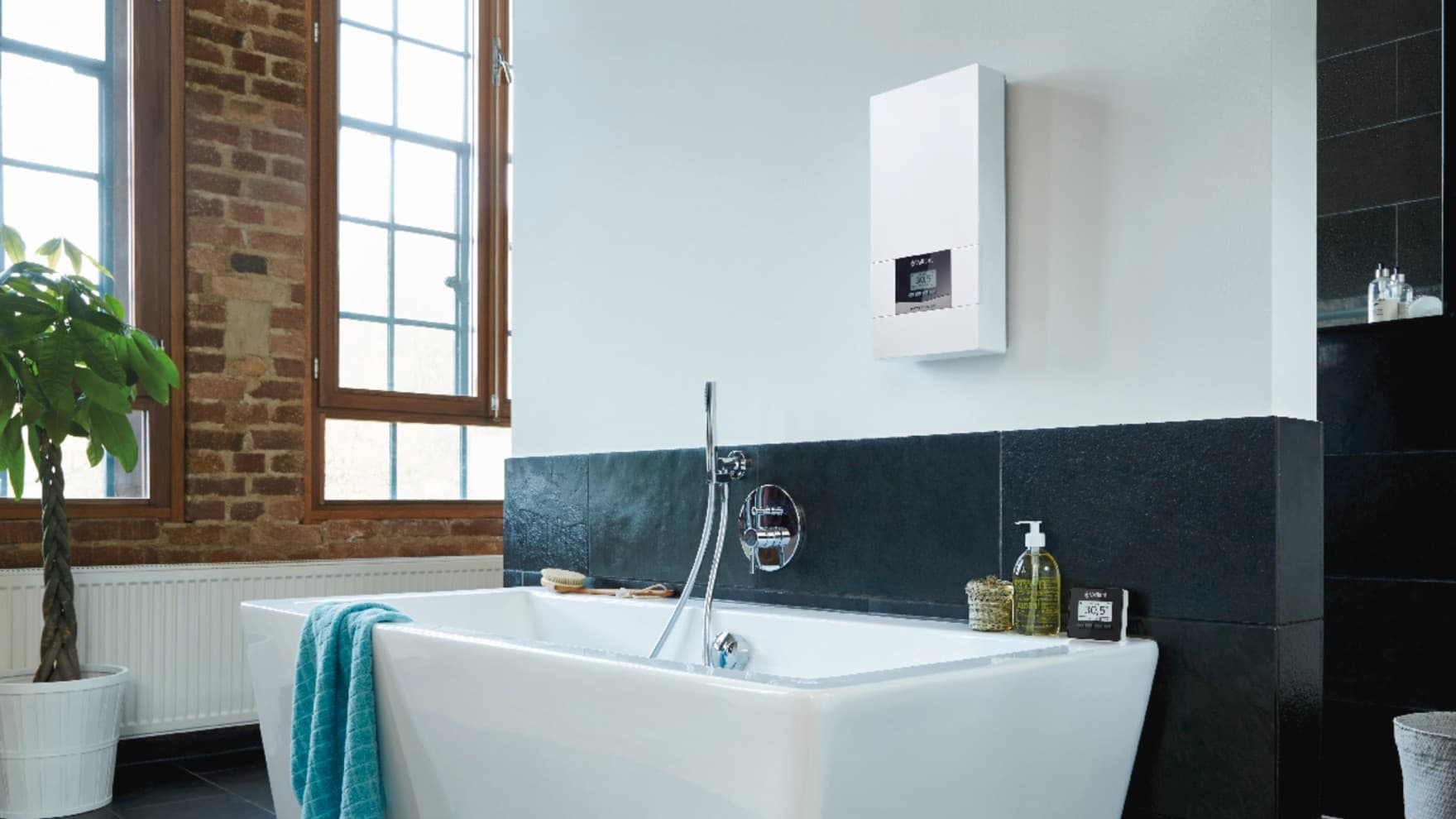 Un chauffe-eau électrique installé au mur d'une salle de bains au-dessus d'une baignoire | Vaillant