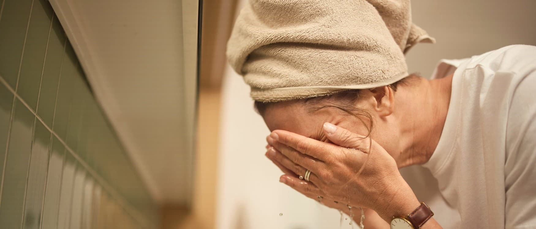 Une femme se lave le visage dans sa salle de bains | Vaillant