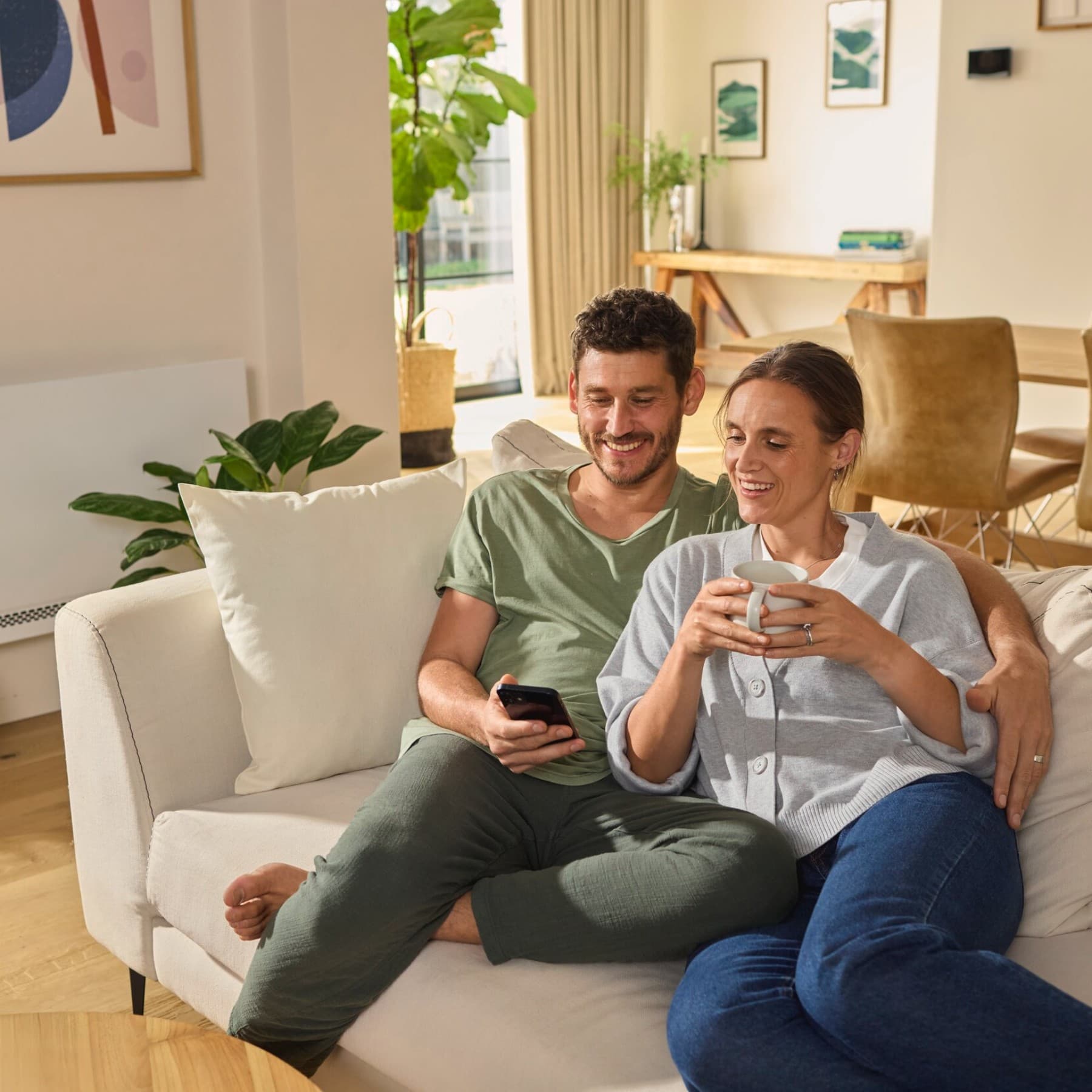 Un couple regarde leur smartphone sur leur canapé | Vaillant