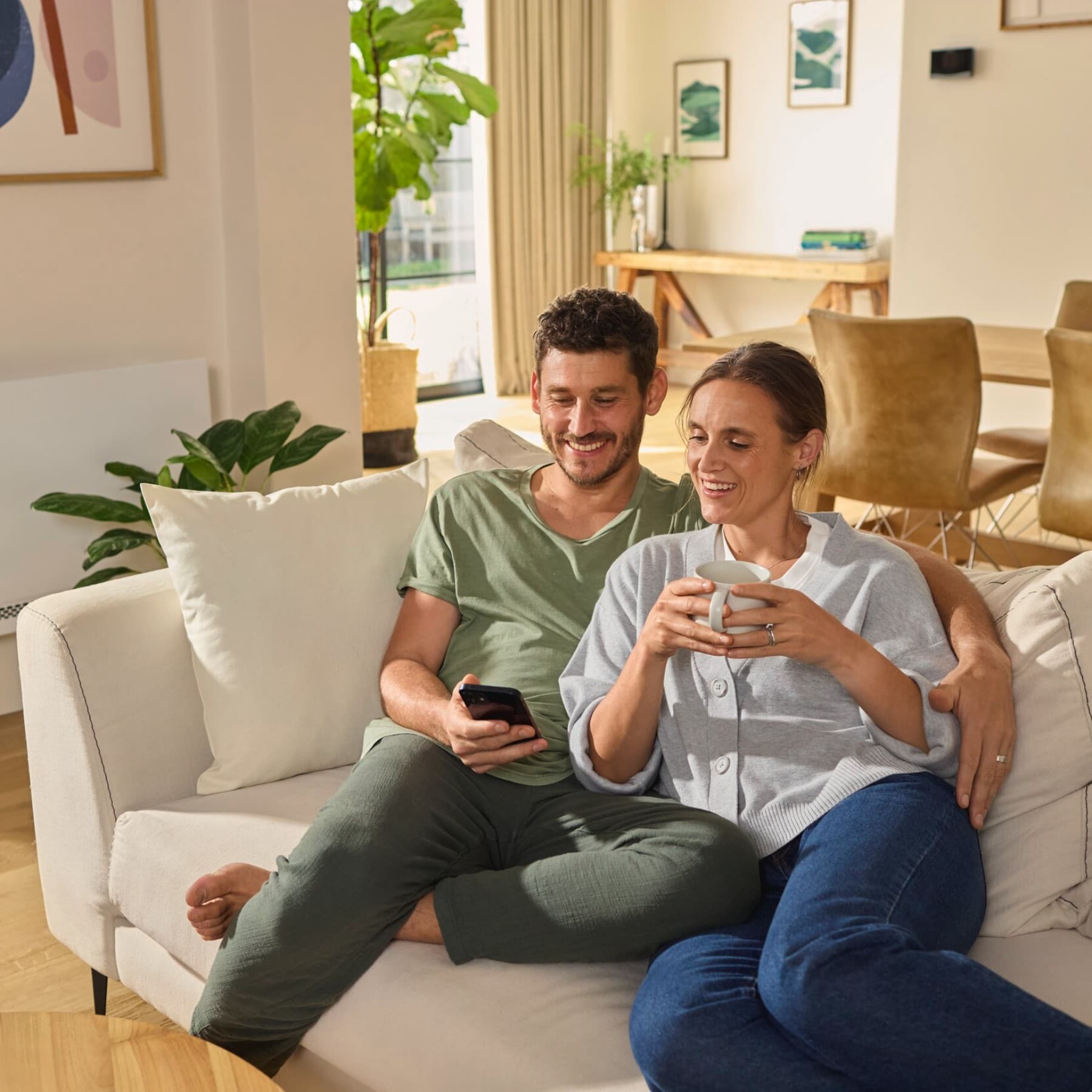 Couple assis sur le canapé regardant un smartphone | Vaillant