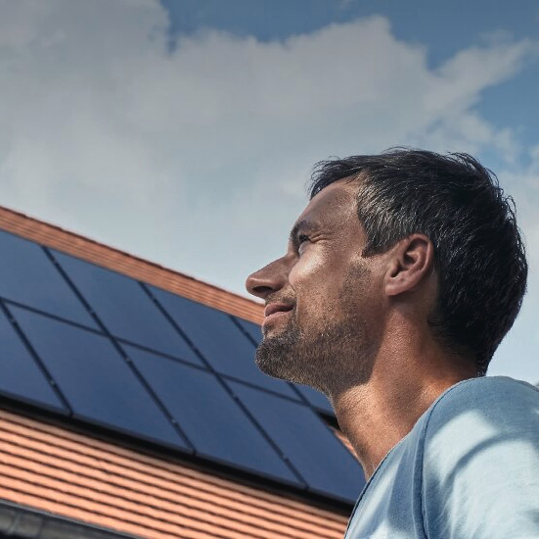 Homme devant un toit équipé de panneaux photovoltaïques | Vaillant