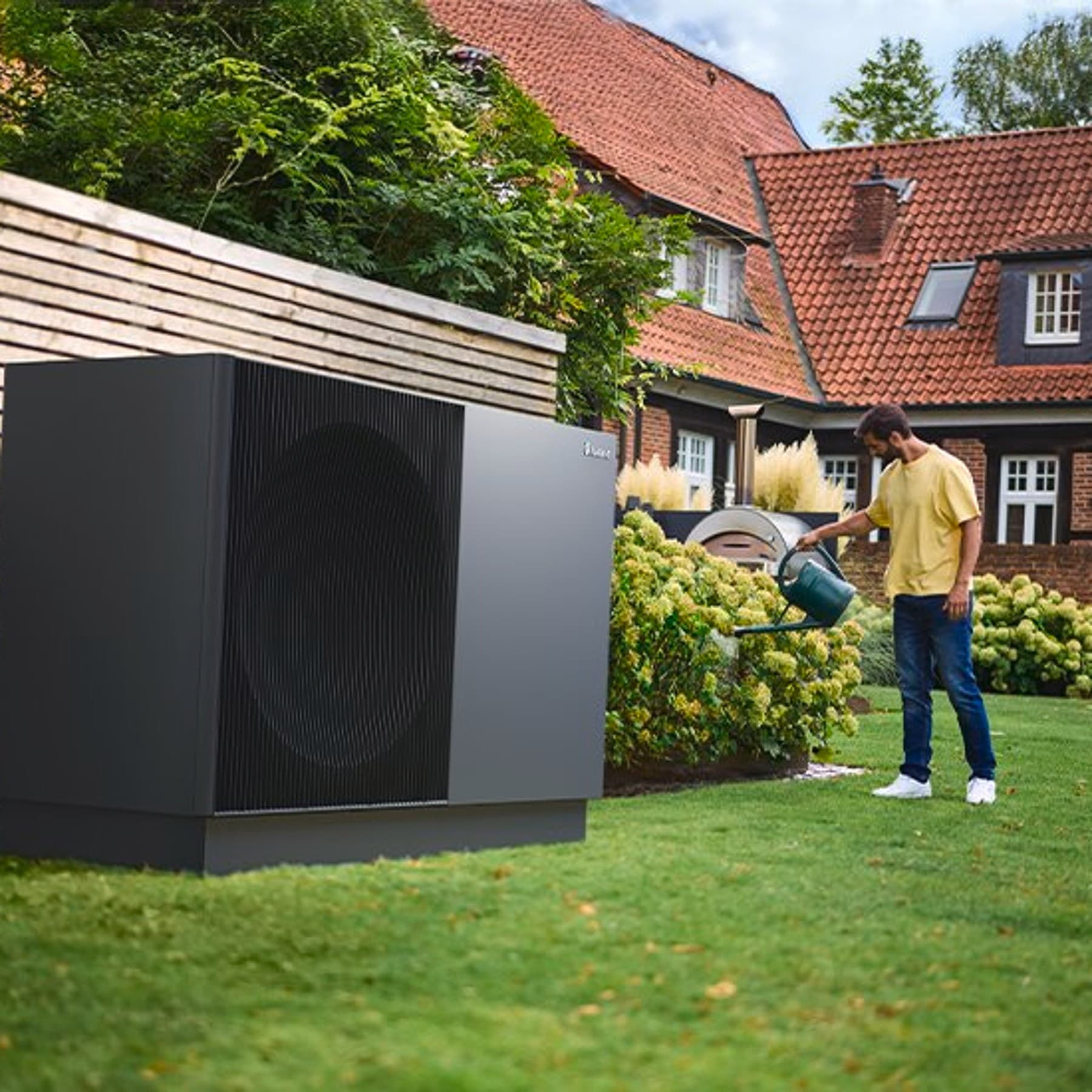 Homme qui arrose des plantes à côtés de aroTHERM perform | Vaillant