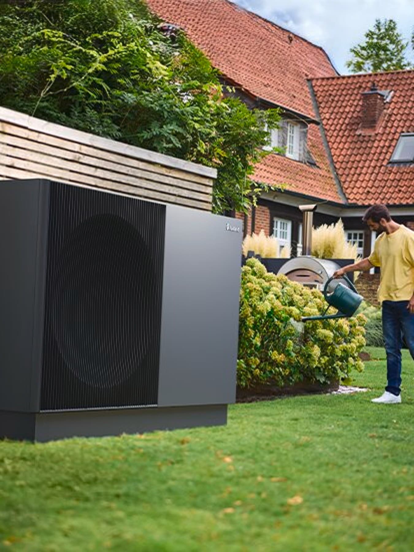 Homme qui arrose des plantes à côtés de aroTHERM perform | Vaillant