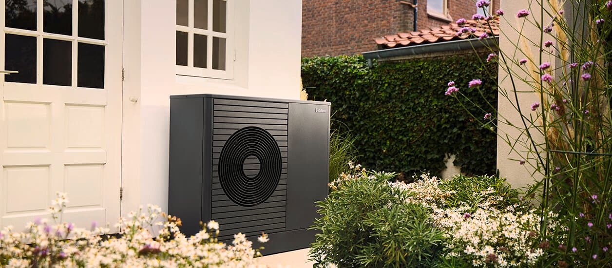 Pompe à chaleur aroTHERM plus installée contre le mur d'une maison | Vaillant