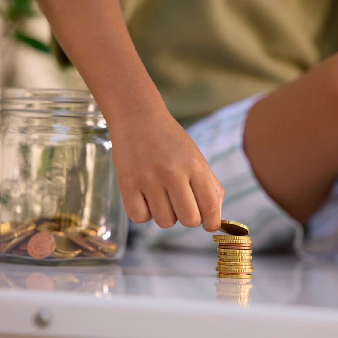 Un enfant compte des pièces de monnaie, assis sur une pompe à chaleur