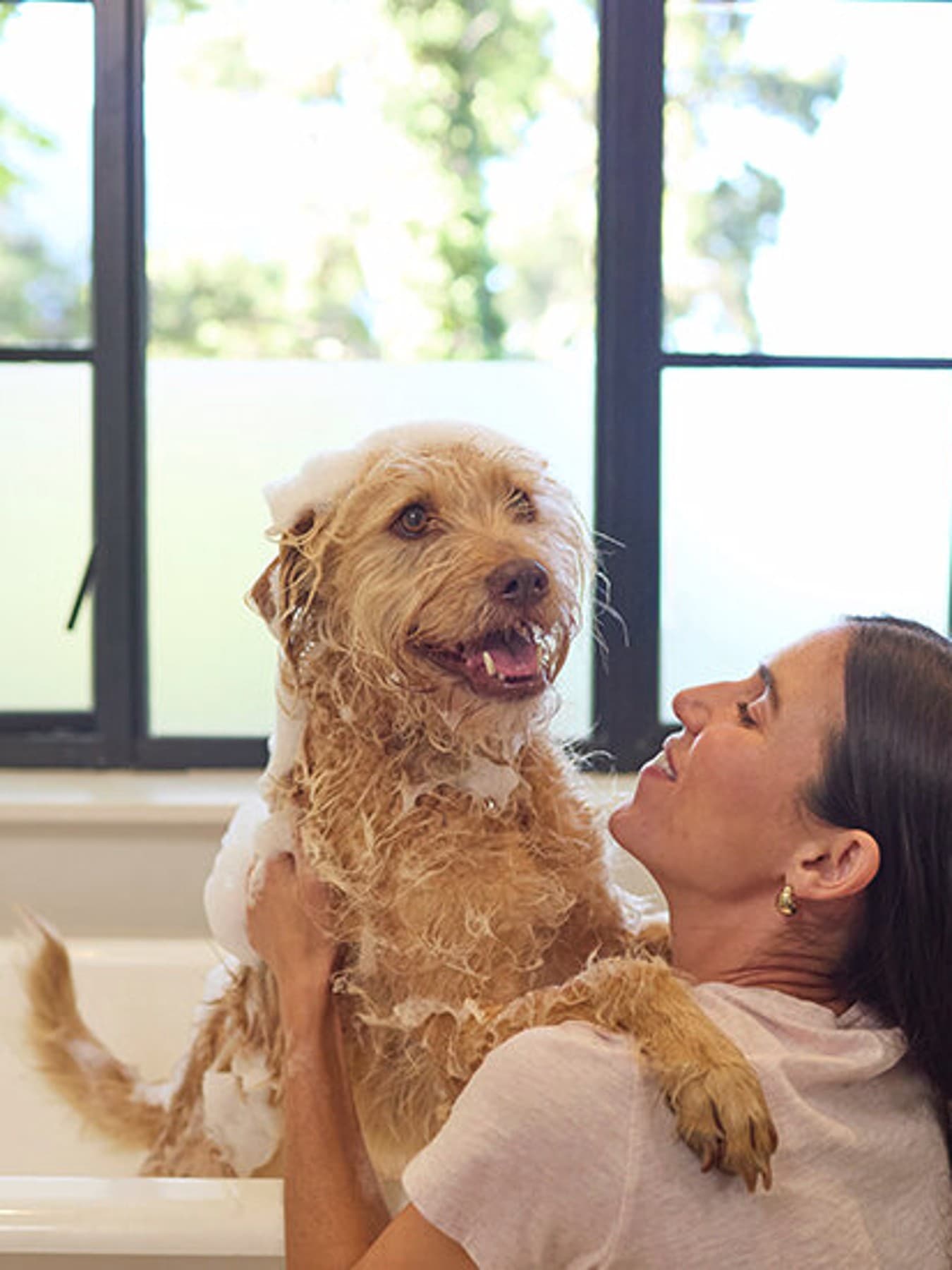 Une femme donne le bain à son chien dans la salle de bain