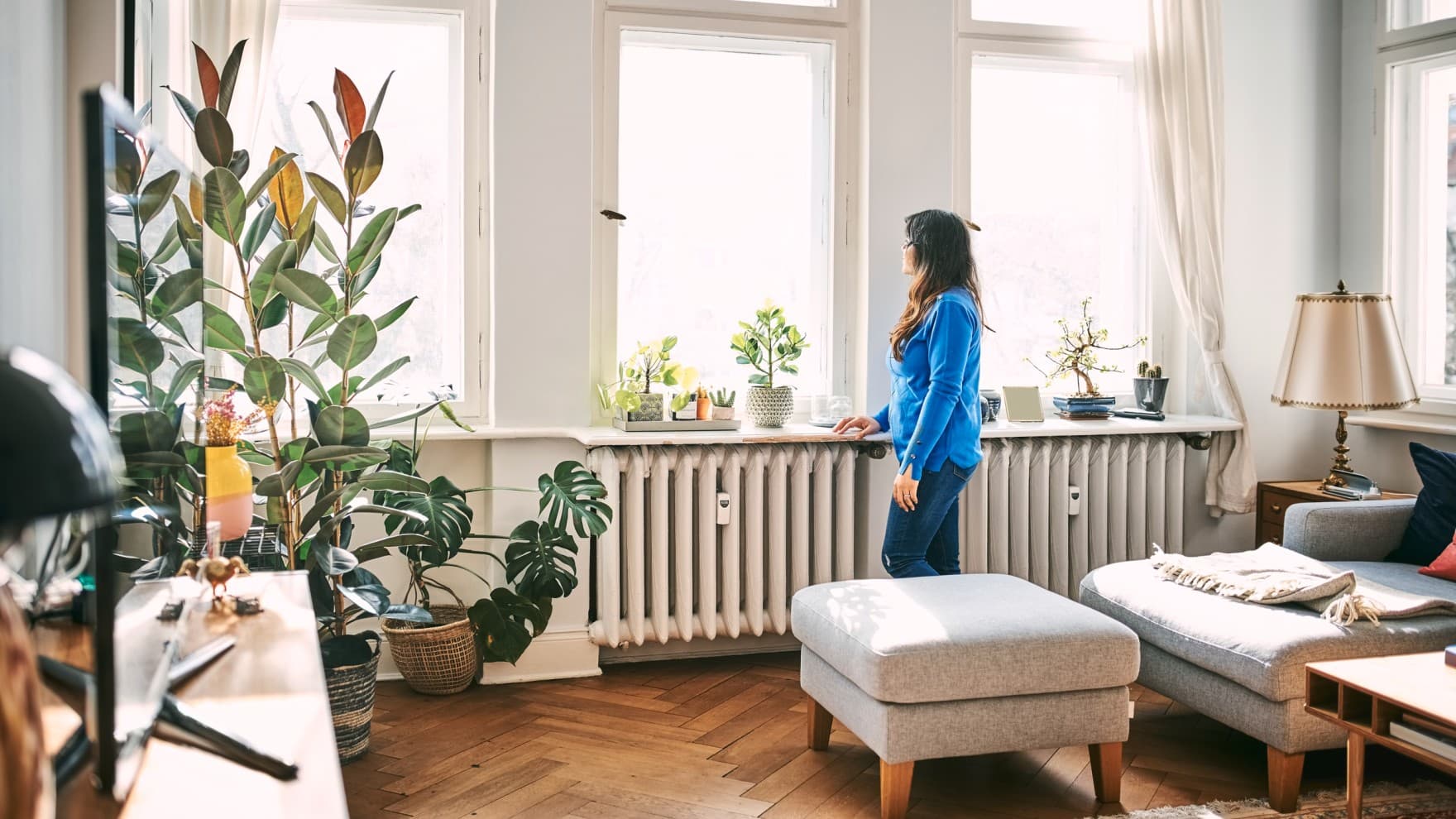 Femme debout dans le salon devant les fenêtres, regardant dehors | Vaillant