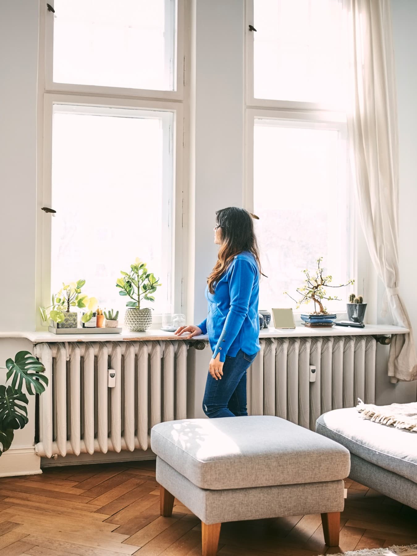 Femme debout dans le salon devant les fenêtres, regardant dehors | Vaillant