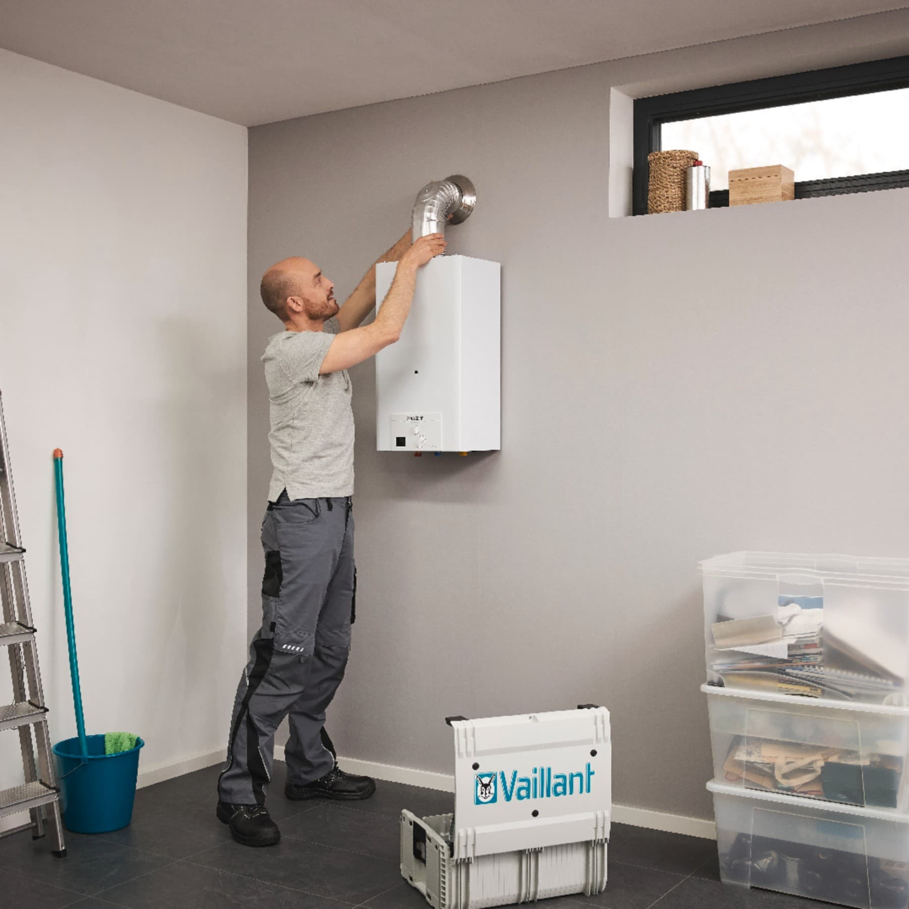 Un installateur finit l'installation d'un chauffe-eau gaz dans un garage | Vaillant