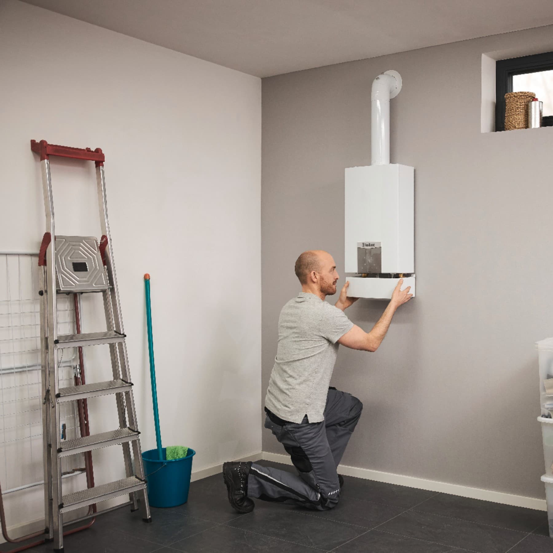 Un installateur en train d'installer un chauffe-eau turboMAG | Vaillant
