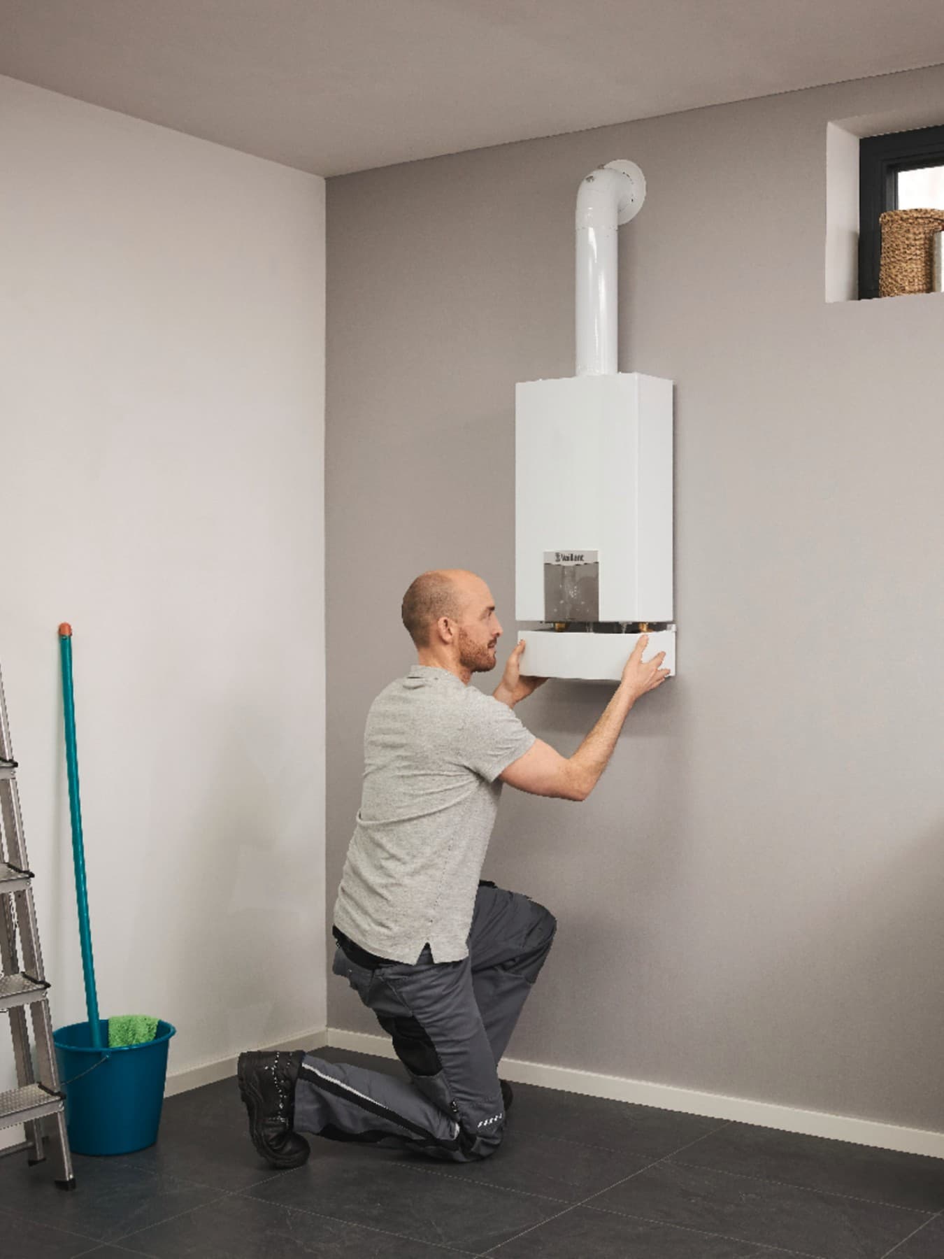 Un installateur en train d'installer un chauffe-eau turboMAG | Vaillant