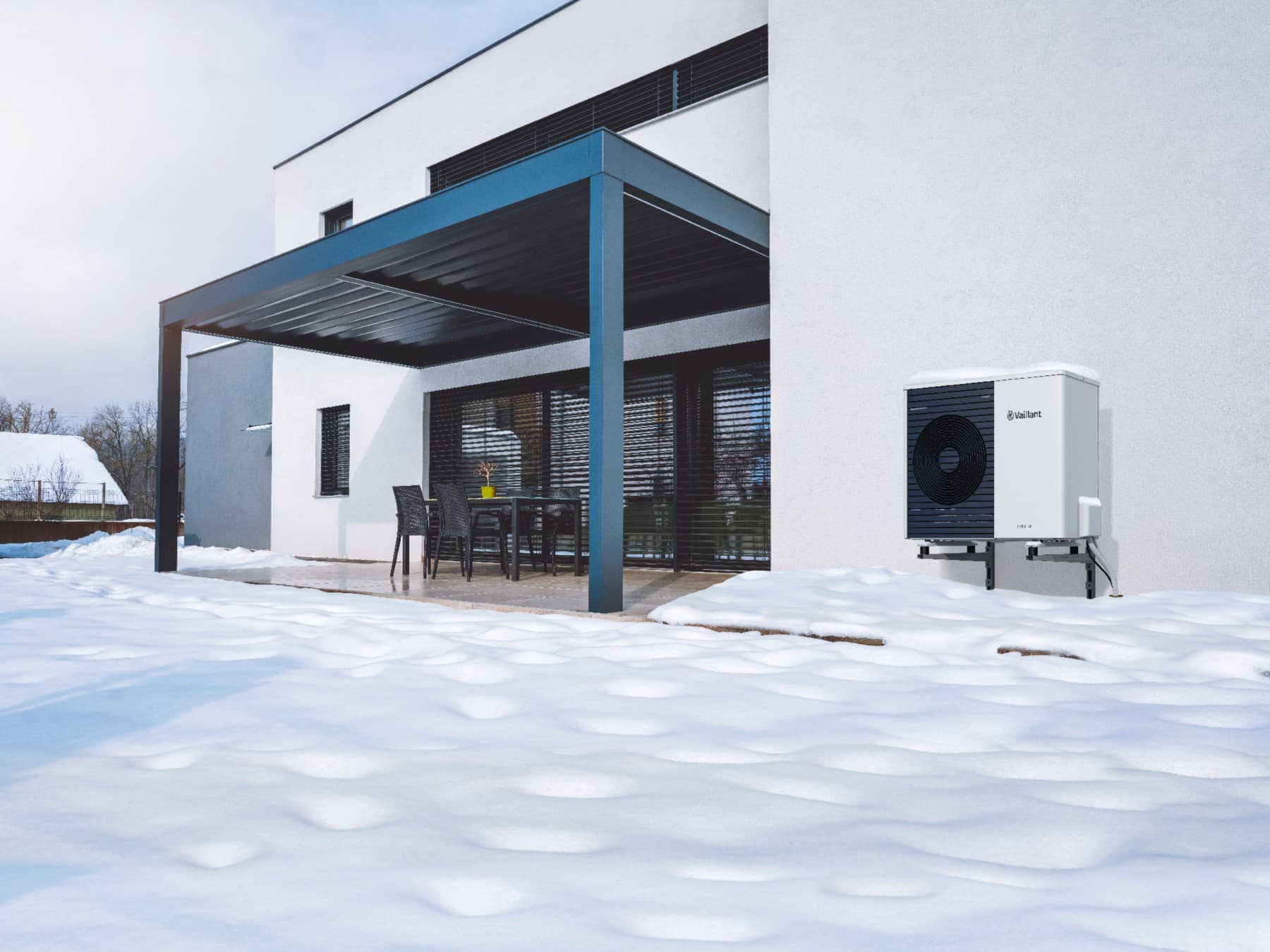 Une unité extérieure de pompe à chaleur installée le long d'une maison sous la neige | Vaillant