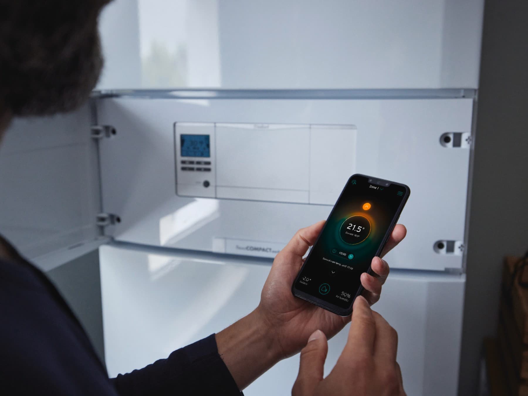 Un homme règle la température sur son téléphone | Vaillant