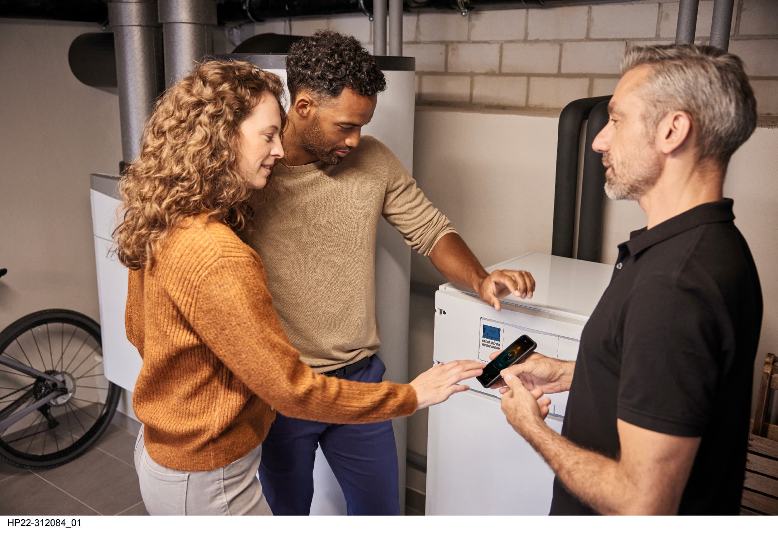 Installateur présentant l'application myVaillant aux propriétaires d'une maison | Vaillant