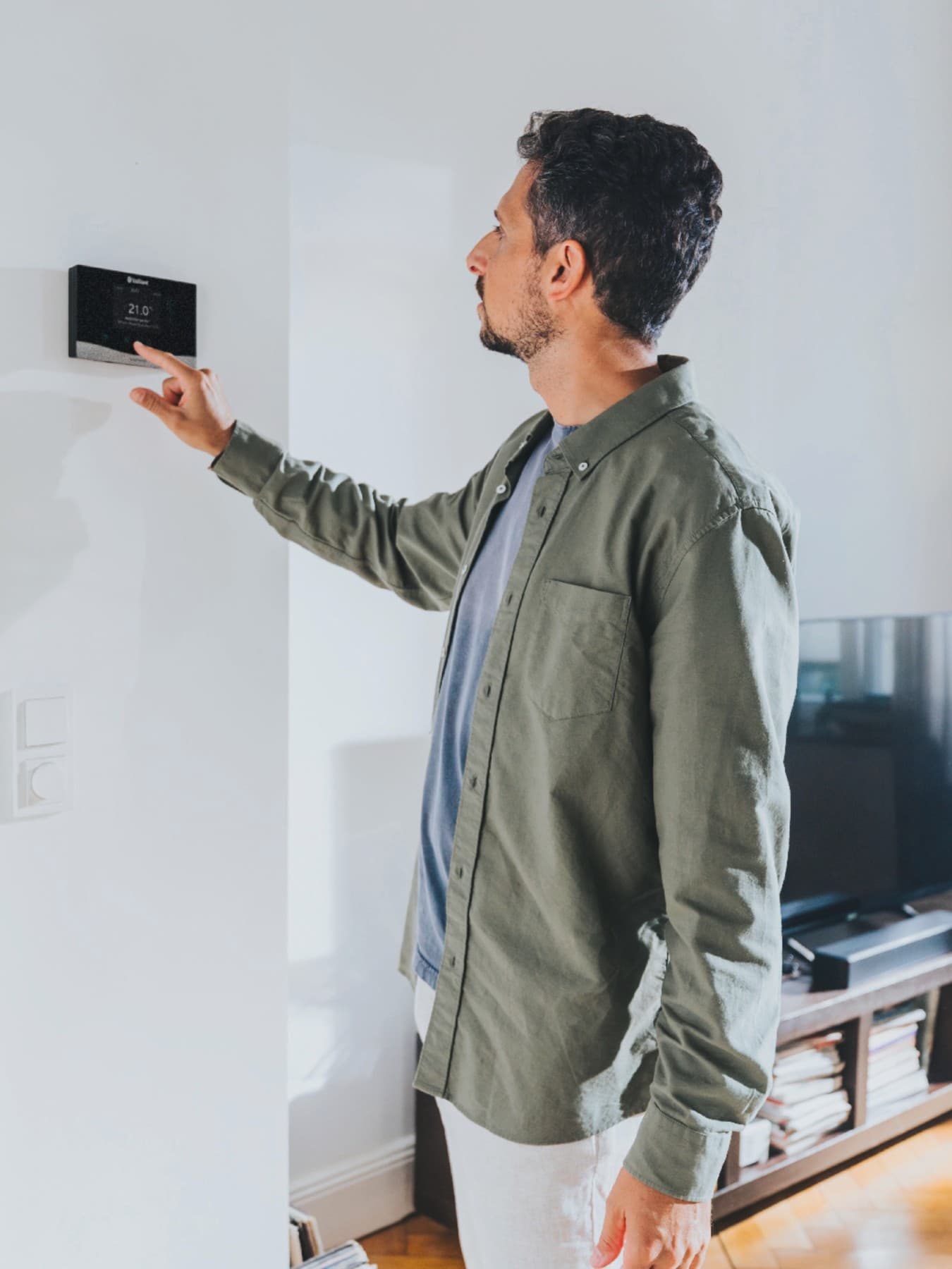 Un homme manipule son régulateur mural | Vaillant