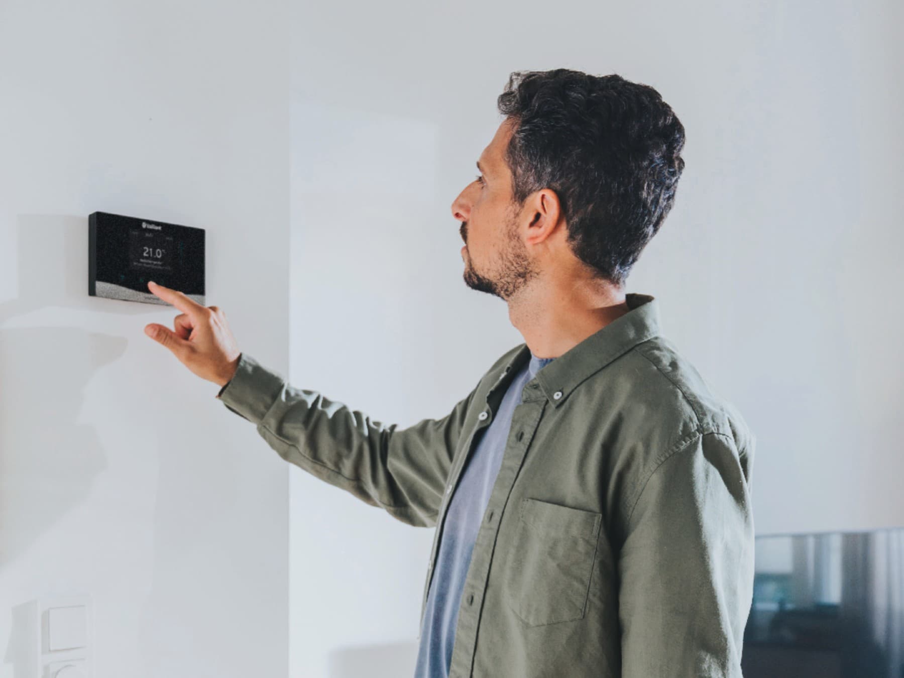 Un homme manipule son régulateur mural | Vaillant