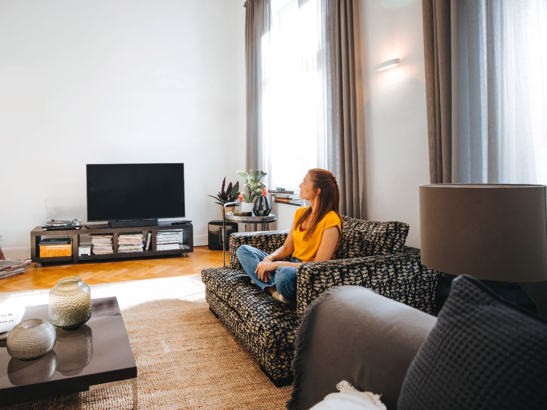 Femme dans un appartement, assise sur un canapé | Vaillant