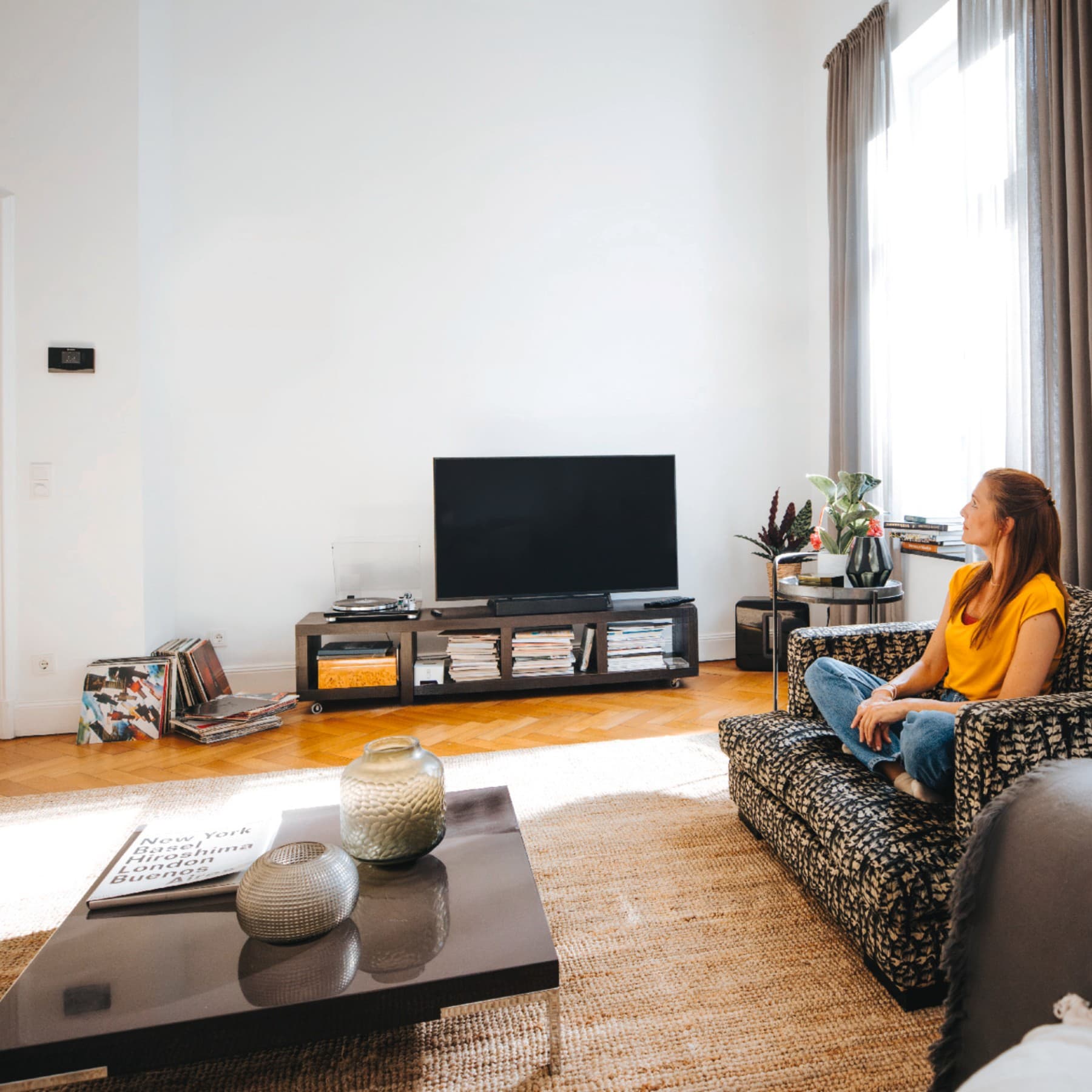 Une femme assise sur son canapé, profitant du calme et de la tranquillité à la température idéale | Vaillant