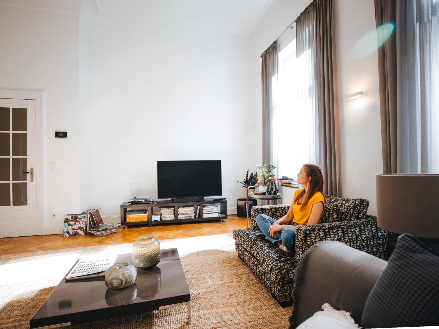 Une femme assise sur son canapé, profitant du calme et de la tranquillité à la température idéale | Vaillant