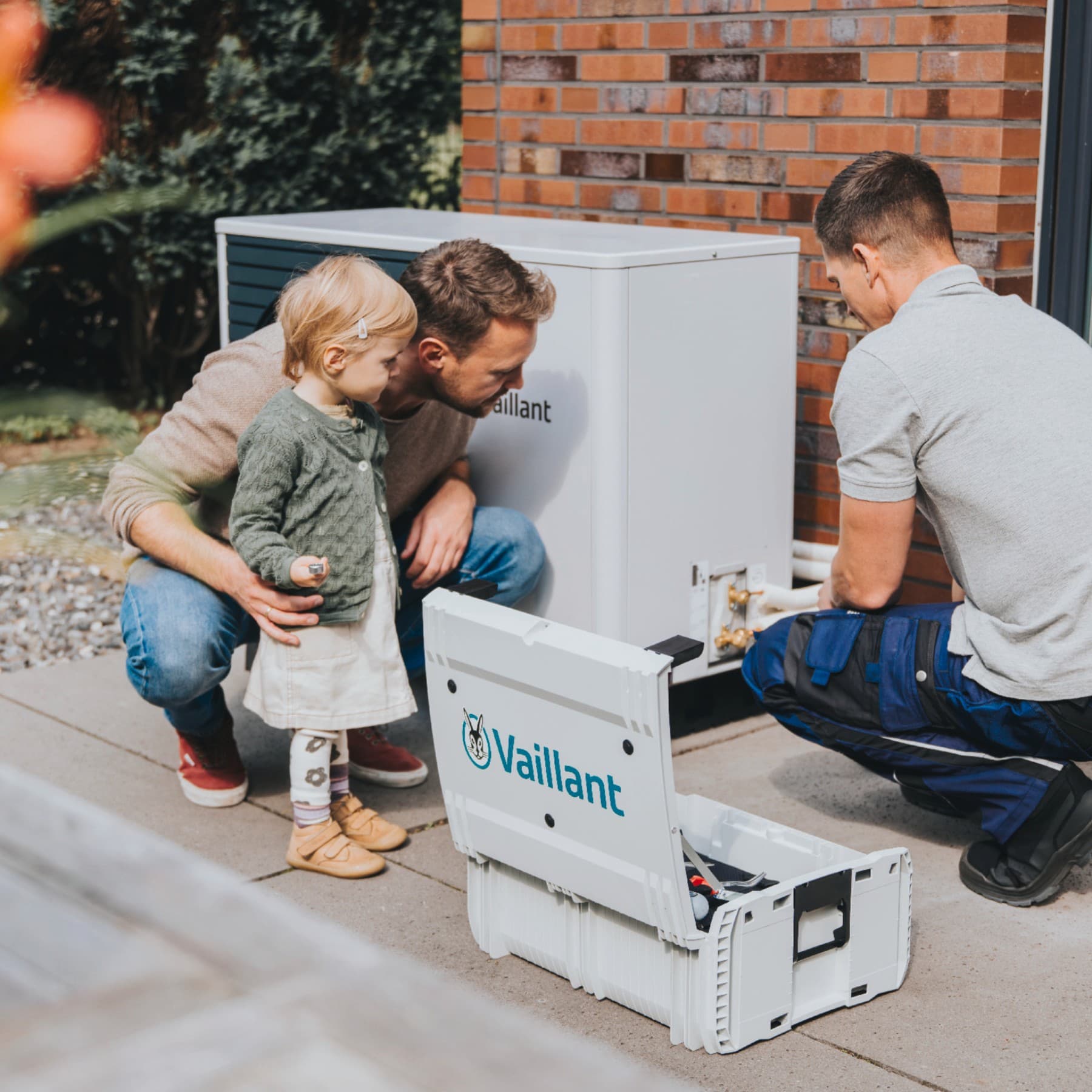 Un père et sa fille regardent un installateur installer une pompe à chaleur | Vaillant