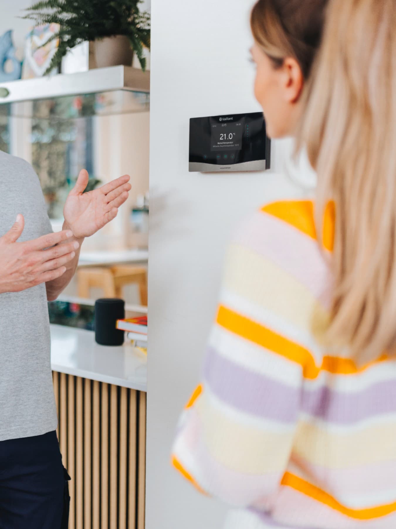installateur montrant à un propriétaire un thermostat fixé au mur | Vaillant