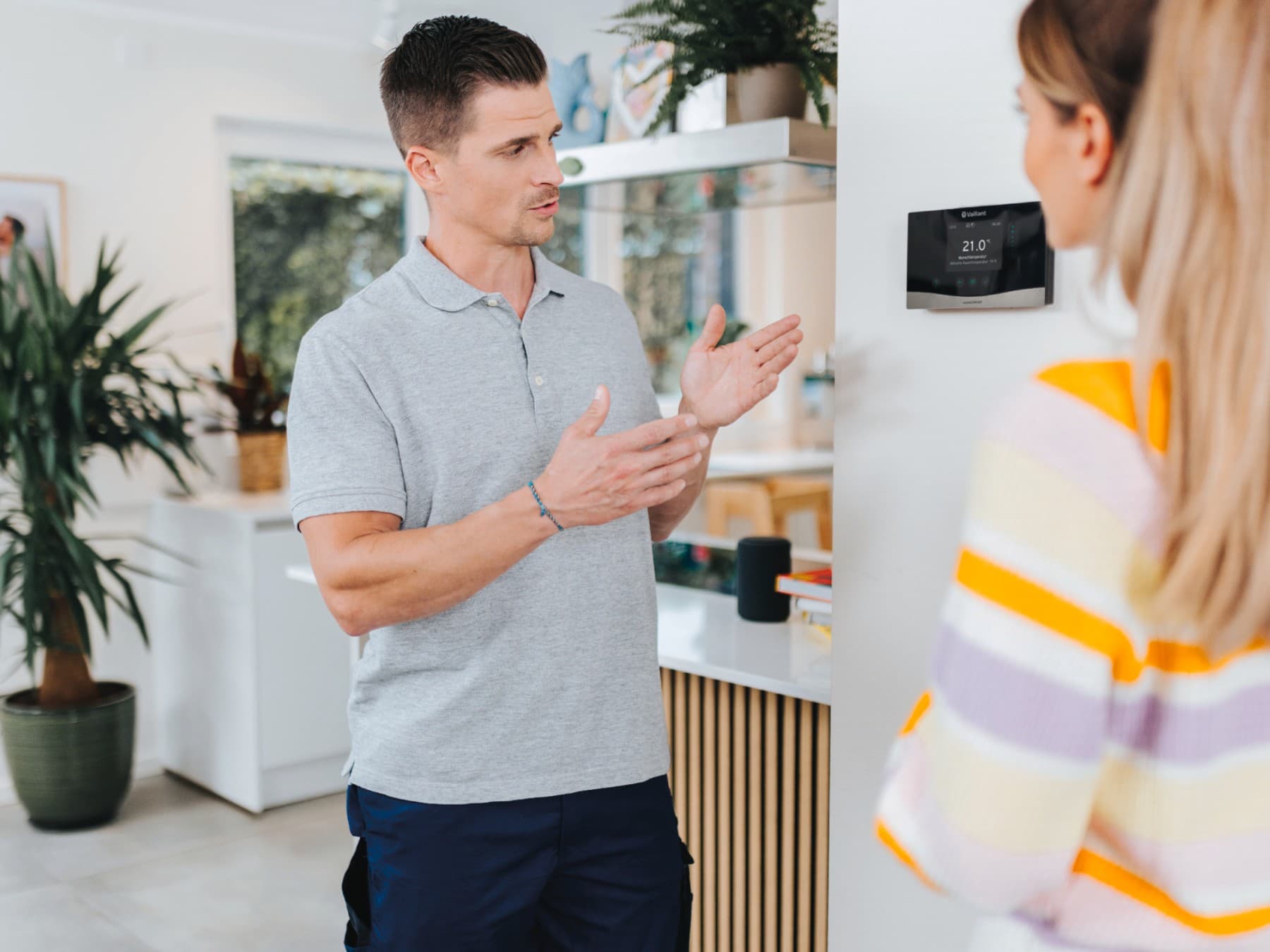 installateur montrant à un propriétaire un thermostat fixé au mur | Vaillant