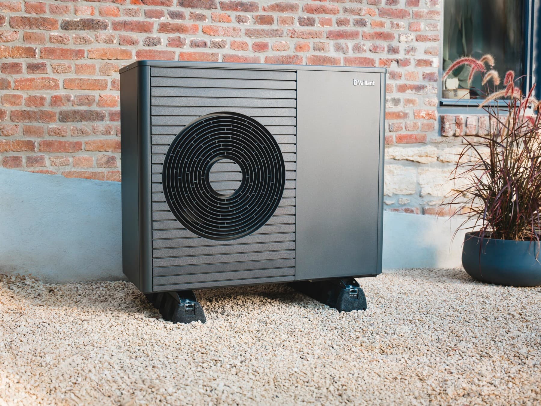 Une unité extérieure d'une pompe à chaleur Vaillant devant un mur en brique | Vaillant