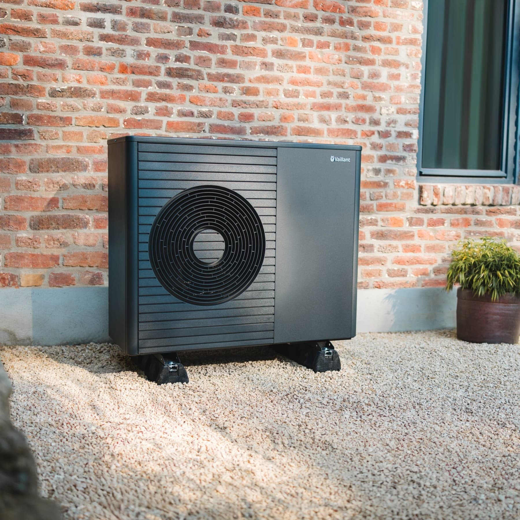 Pompe à chaleur devant une maison en briques | Vaillant