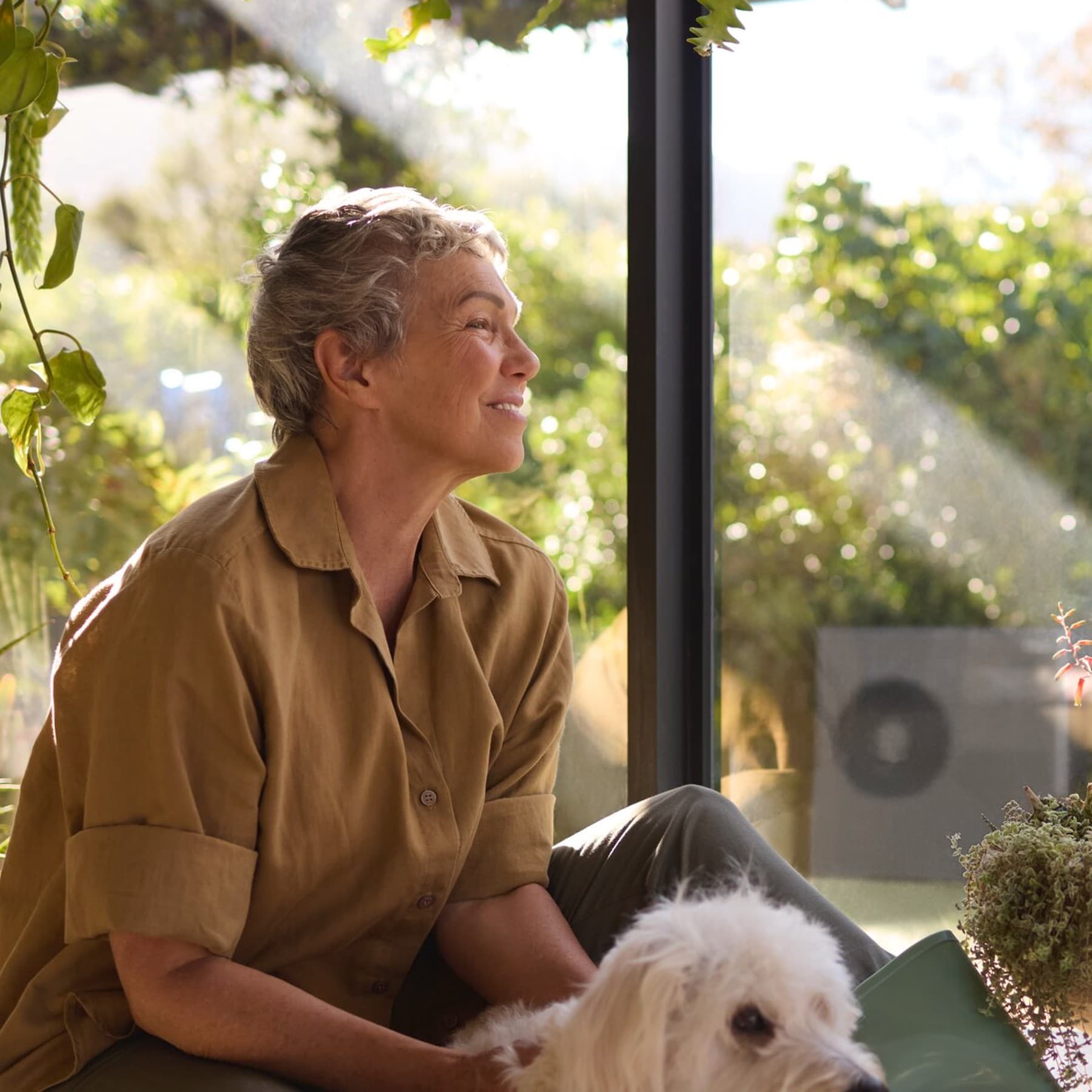 Une femme assise près de la fenêtre avec son chien | Vaillant